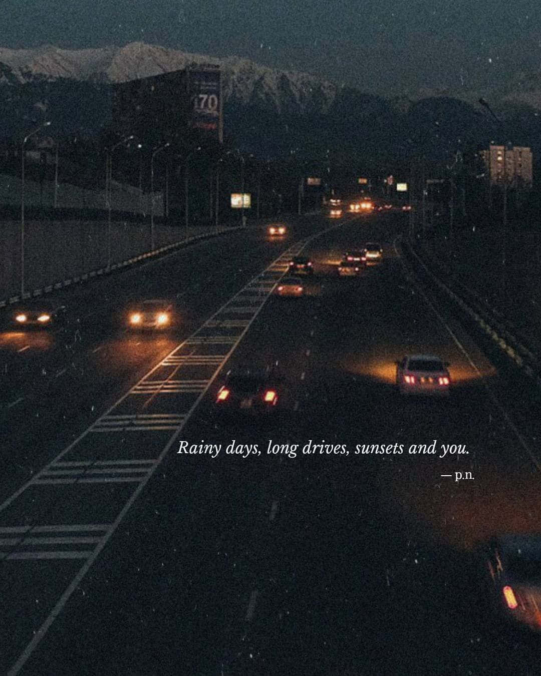 桌布 壁紙 — 一個下雨的夜晚，高速公路上的車頭燈和尾燈閃爍，蜿蜒通向黑暗天空下積雪的山峰。