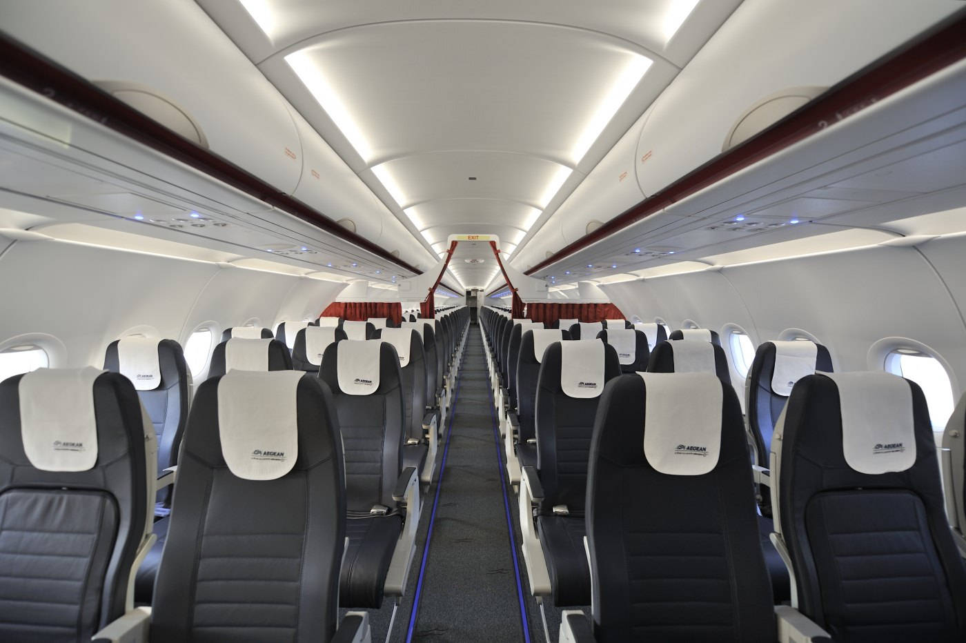 Plane 桌布 壁紙 — 一個乾淨現代的飛機客艙，在明亮的頭頂燈光下，有一排排黑色皮革座椅朝前。