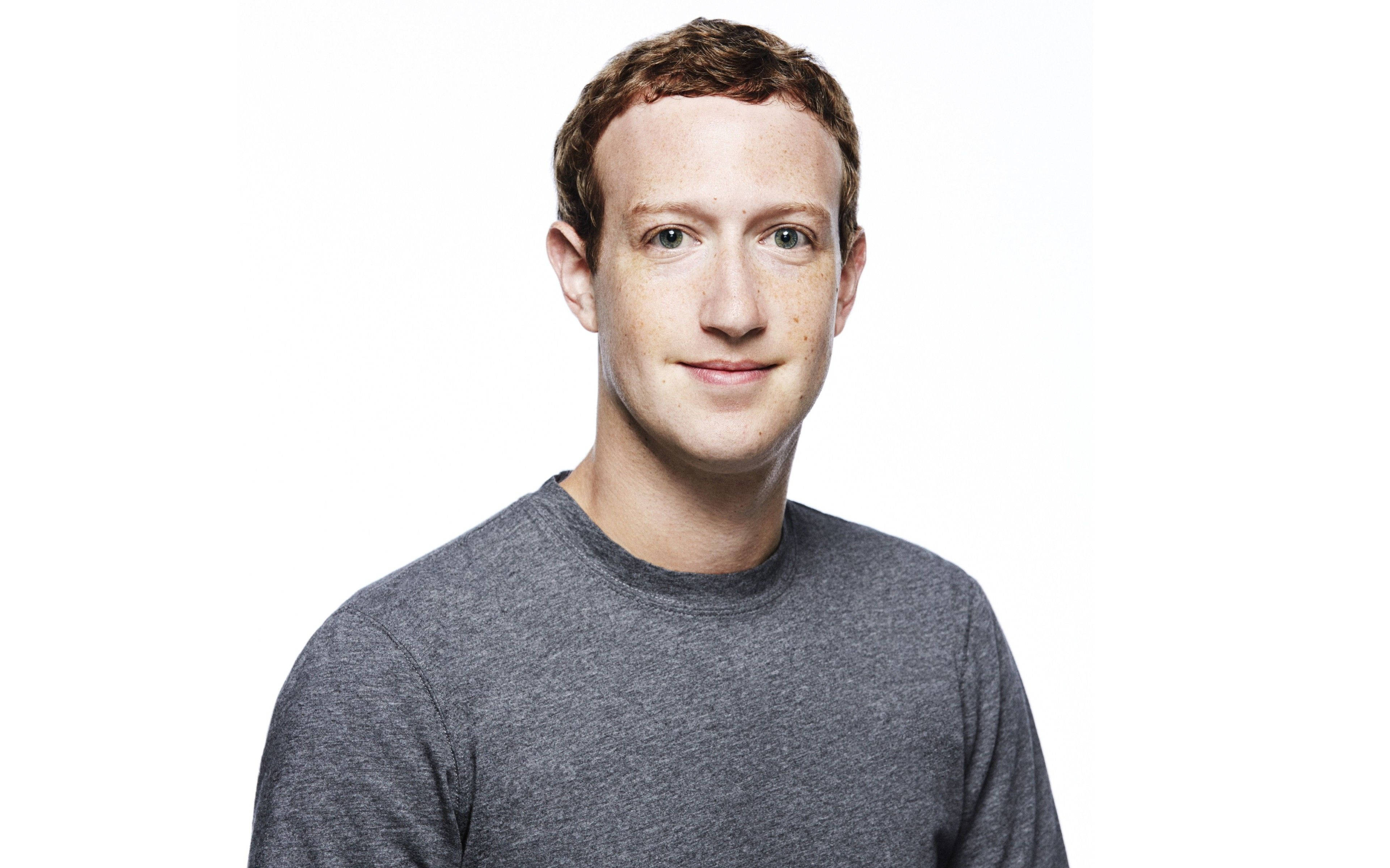 Zuckerberg 桌布 壁紙 — 一個乾淨的肖像，展示一位有雀斑和短棕髮的男士，穿著灰色T恤，背景為白色。