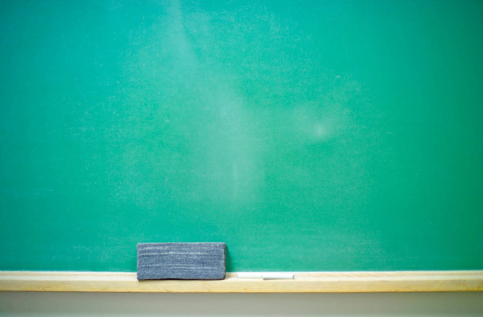 Education 桌布 壁紙 — 一個乾淨的青綠色黑板，上面放著灰色板擦和白色粉筆，擱在木製邊緣上。