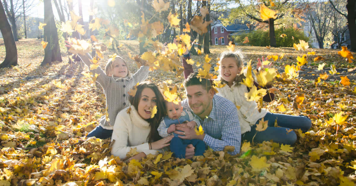 Fall Family 桌布 壁紙 — 一個五口之家在陽光明媚的秋日公園裡笑著拋灑金色的楓葉。