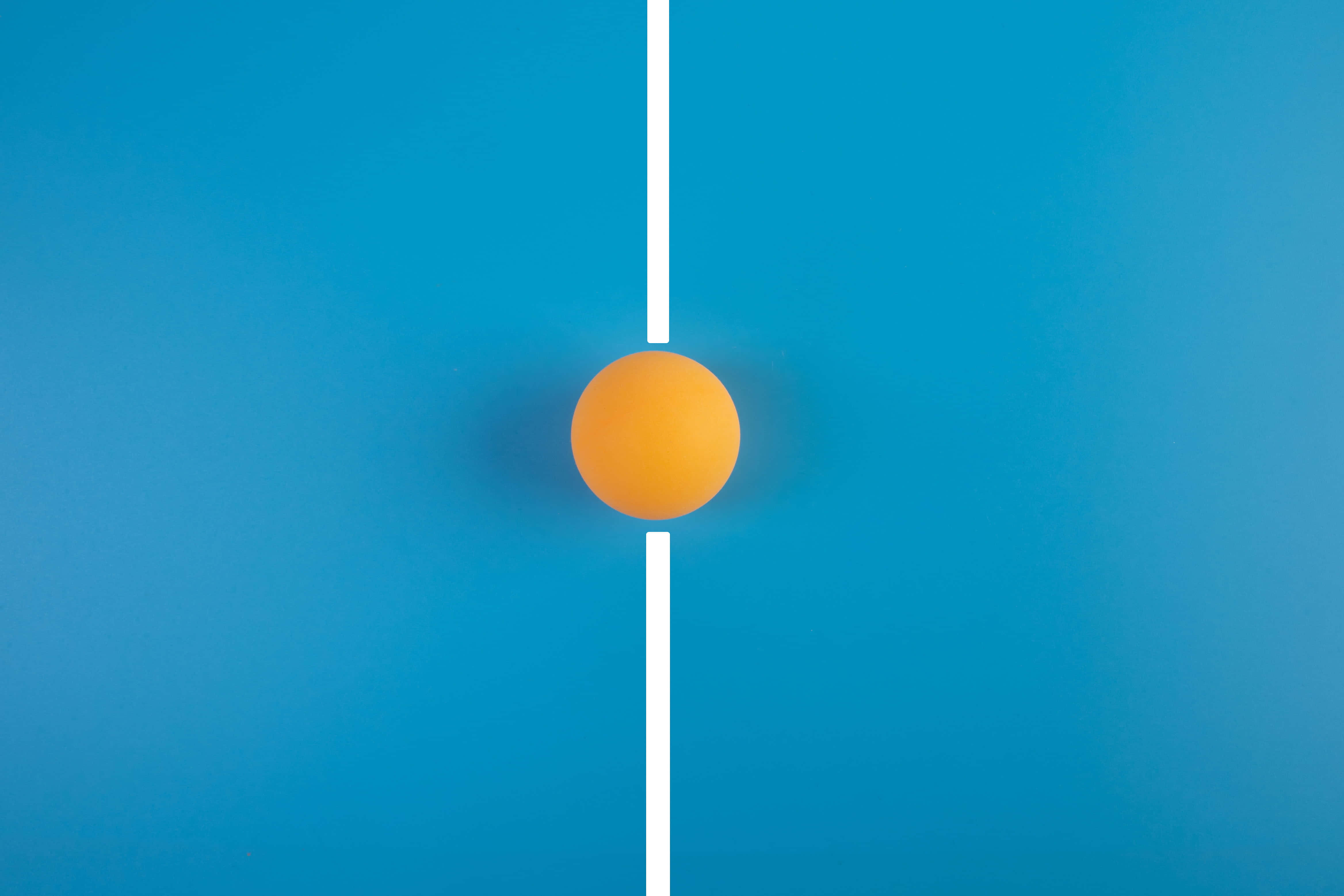 Table Tennis 桌布 壁紙 — 一個亮橙色的乒乓球放在純藍色背景的白色線上，居中放置。