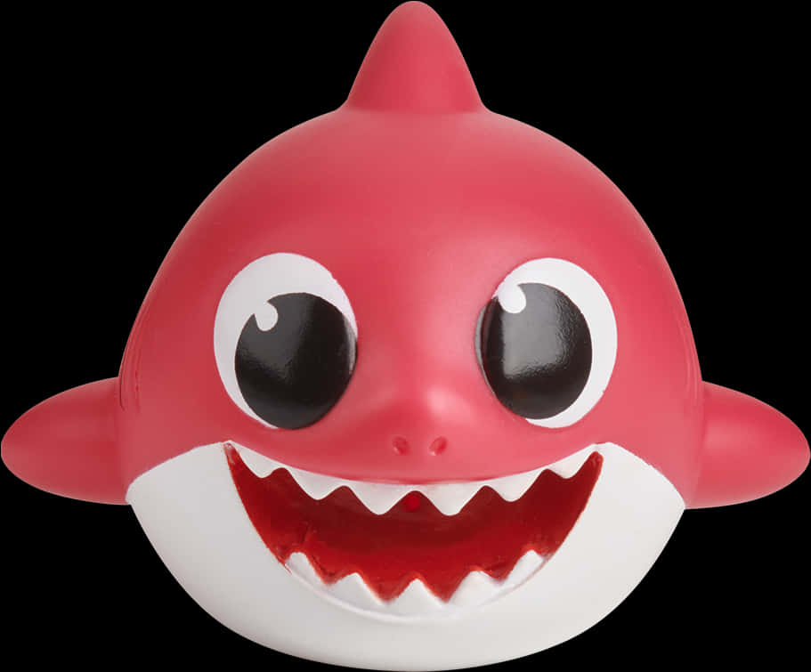 baby shark 桌布 壁紙 — 一個亮粉紅色卡通鯊魚玩具，有大大的圓眼睛和露出牙齒的寬闊笑容，背景為黑色。