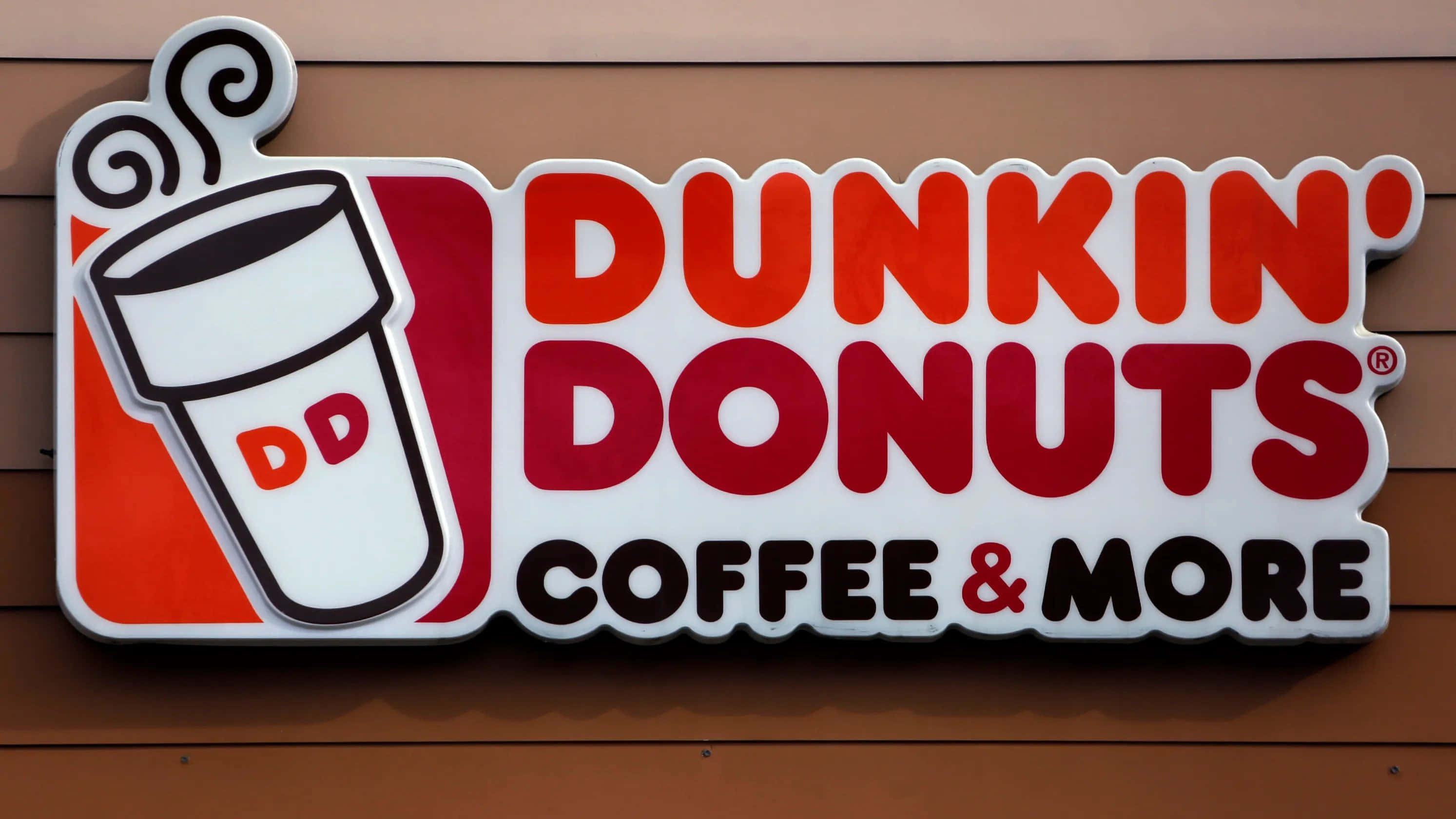 Dunkin Donuts 桌布 壁紙 — 一個亮紅色和白色的Dunkin' Donuts標誌，帶有咖啡杯標誌，安裝在棕色木牆上。