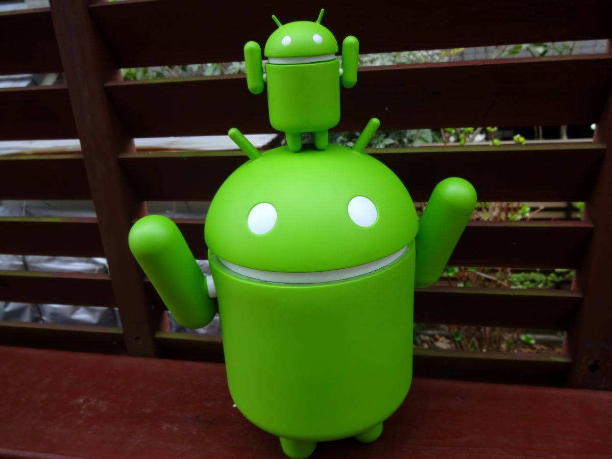 Android Developer 桌布 壁紙 — 一個亮綠色的Android吉祥物公仔坐在木長凳上，頭頂有個較小的版本。