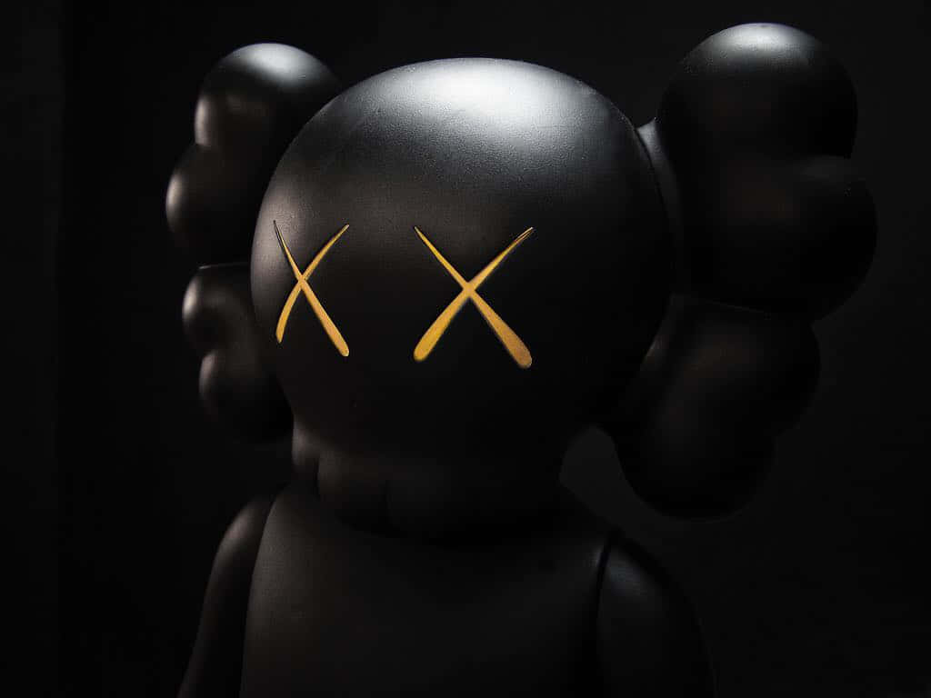 Kaws Astro Boy 桌布 壁紙 — 一個亮面黑色KAWS公仔，帶有金色X眼睛，在深色背景下形成強烈對比。