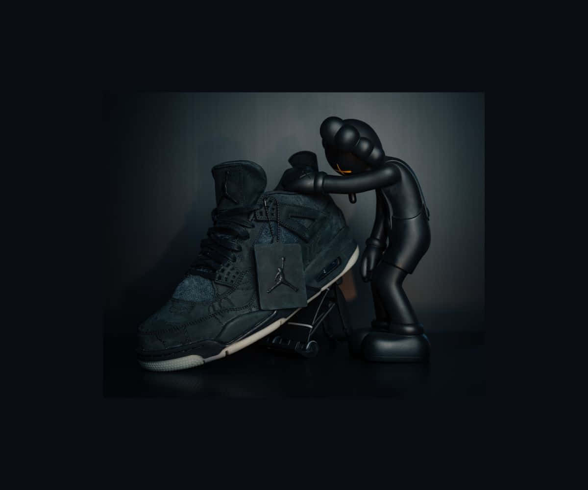 Kaws X Air Jordan 桌布 壁紙 — 一個亮面黑色KAWS公仔溫柔地擁抱一雙深灰色Jordan運動鞋，背景是充滿氛圍的漸層色。