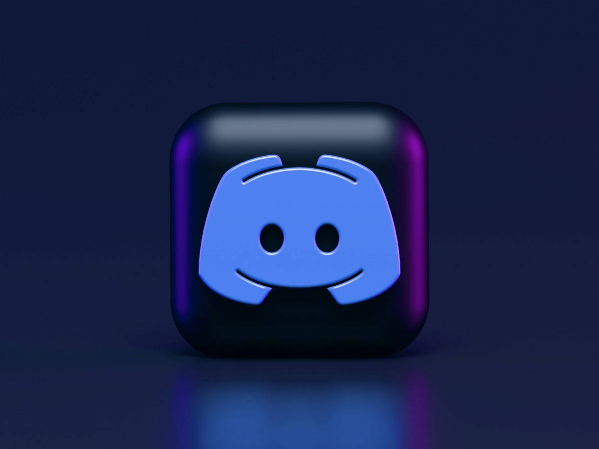 Discord 桌布 壁紙 — 一個亮面黑色應用程式圖示，中央帶有發光藍色 Discord 標誌，置於帶有紫色和藍色燈光的深色漸變背景上。