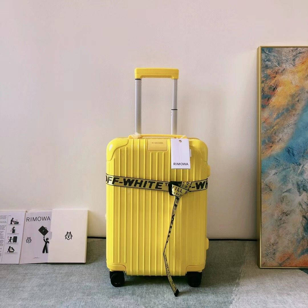 手機 桌布 壁紙 — 一個亮黃色的RIMOWA行李箱，配有OFF-WHITE帶子，直立於簡約房間內，旁邊有抽象藝術品和品牌盒子。