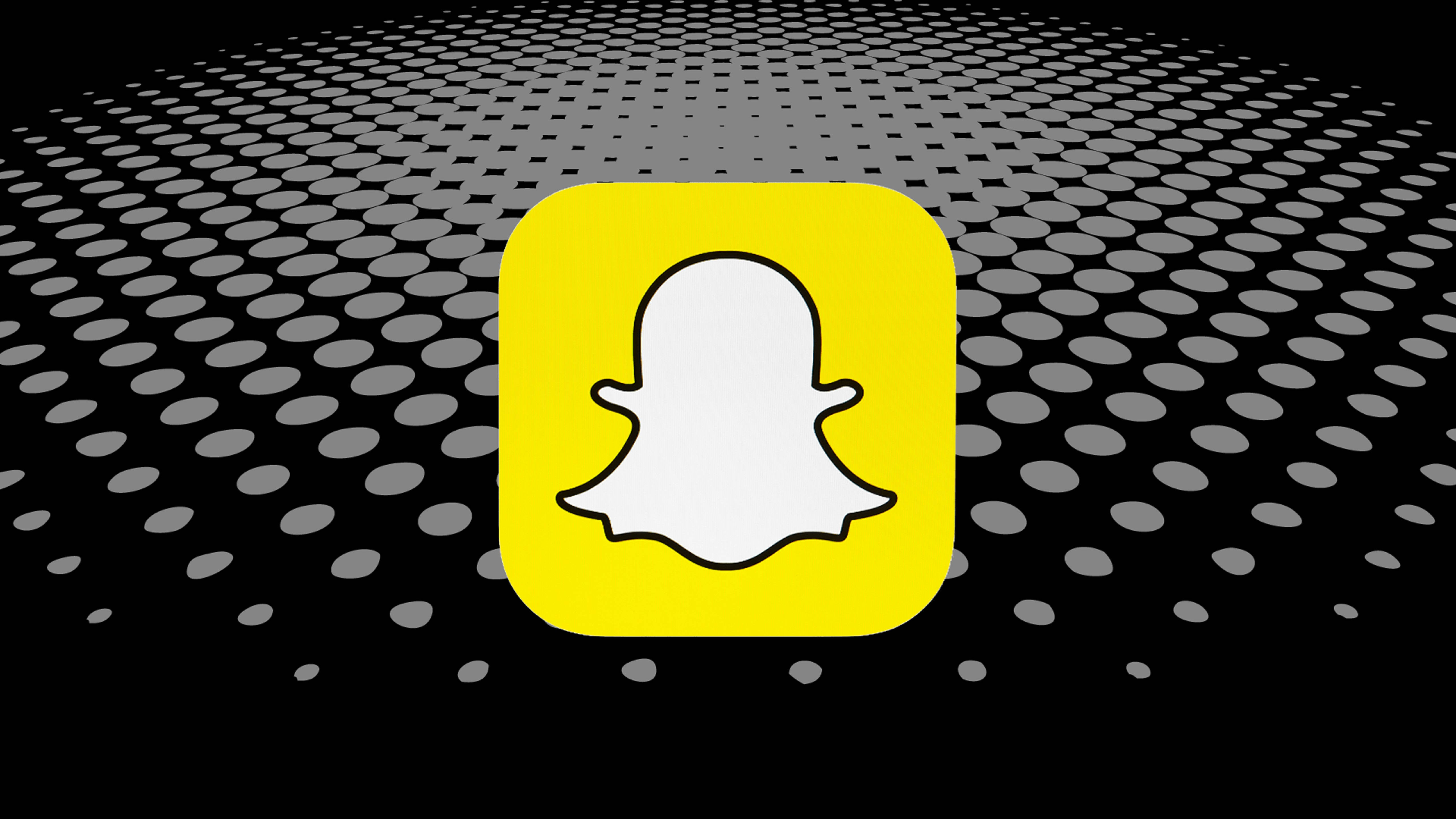 Snapchat 桌布 壁紙 — 一個亮黃色的Snapchat鬼魂圖示，居中於黑色背景上，帶有後退的灰色圓點圖案。