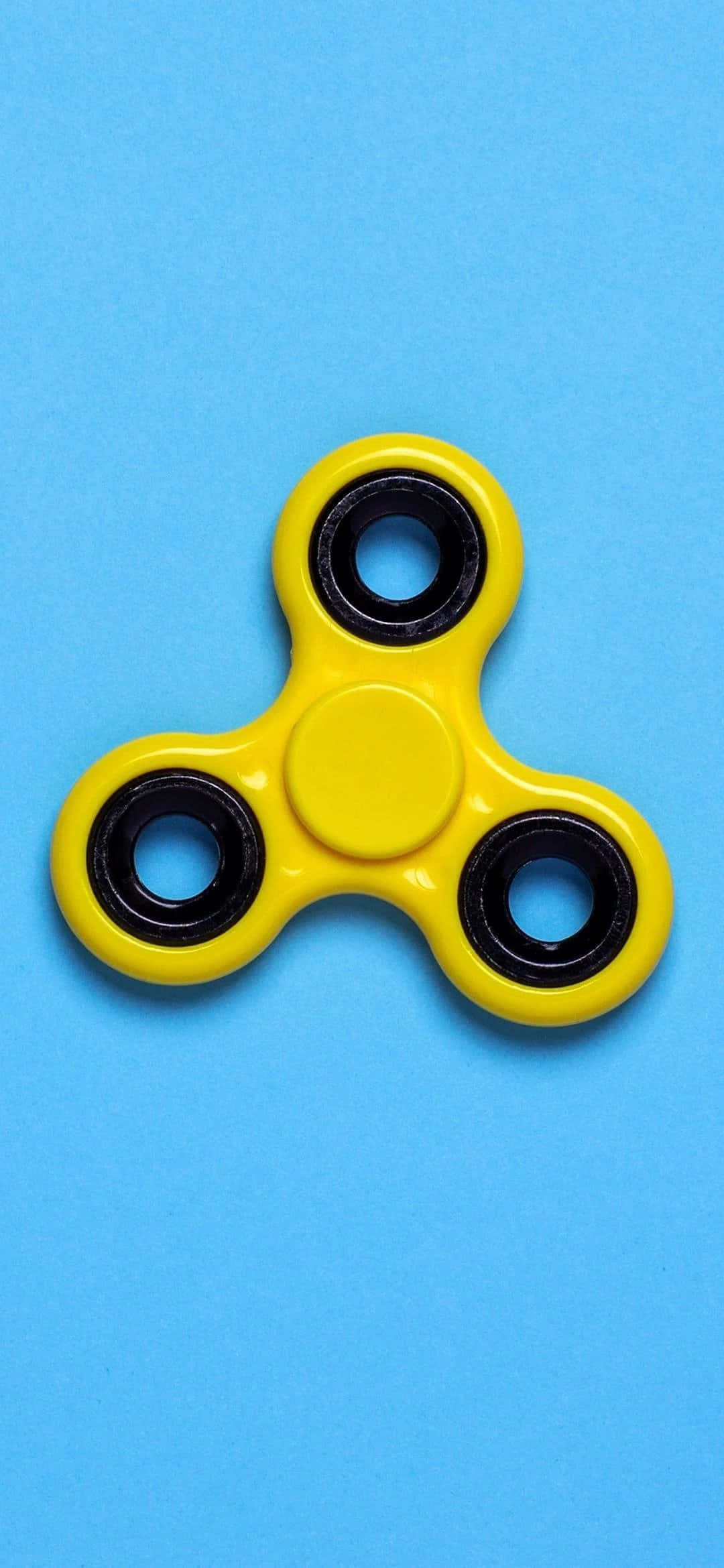 Fidget 桌布 壁紙 — 一個亮黃色的指尖陀螺帶黑色軸承，居中放置在純藍色背景上。