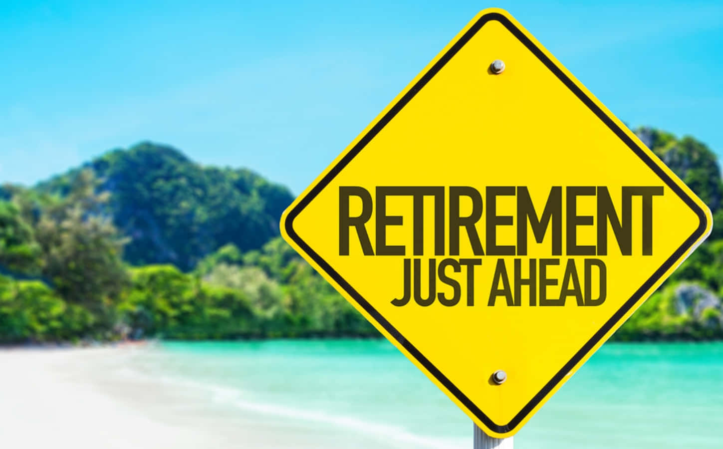 Retirement 桌布 壁紙 — 一個亮黃色菱形標誌，上面寫著「retirement just ahead」，矗立在熱帶海灘前，背景是碧綠的海水、茂密的綠色山丘和清澈的藍天。