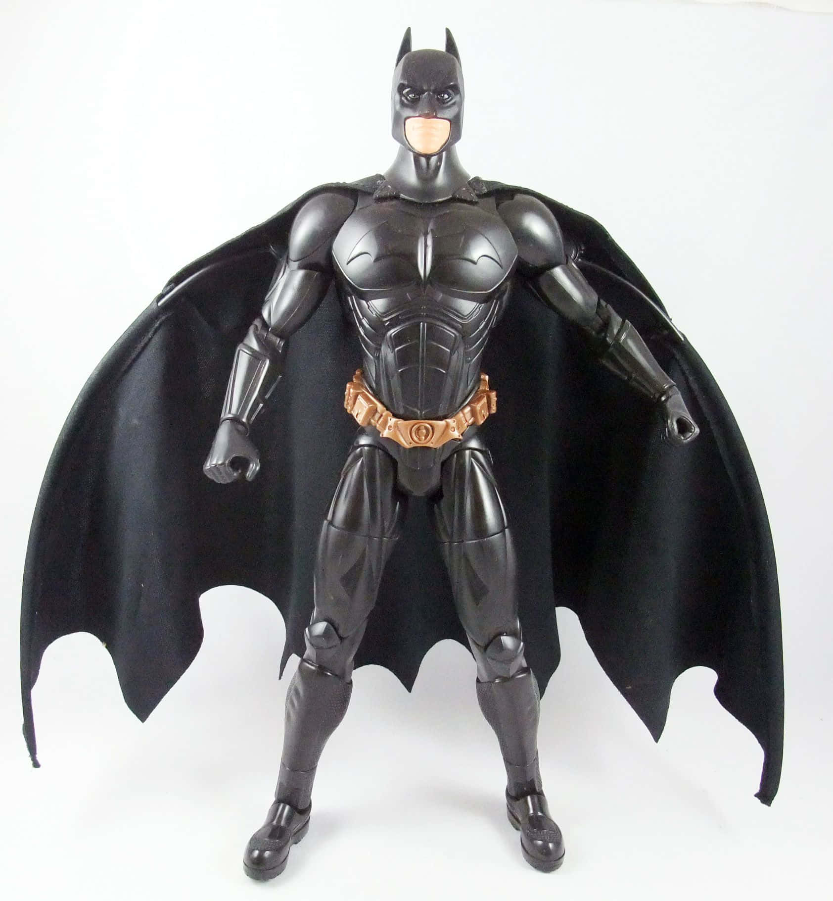Batman Begins 桌布 壁紙 — 一個亮黑色蝙蝠俠動作人偶，披風展開，站在純白背景前。
