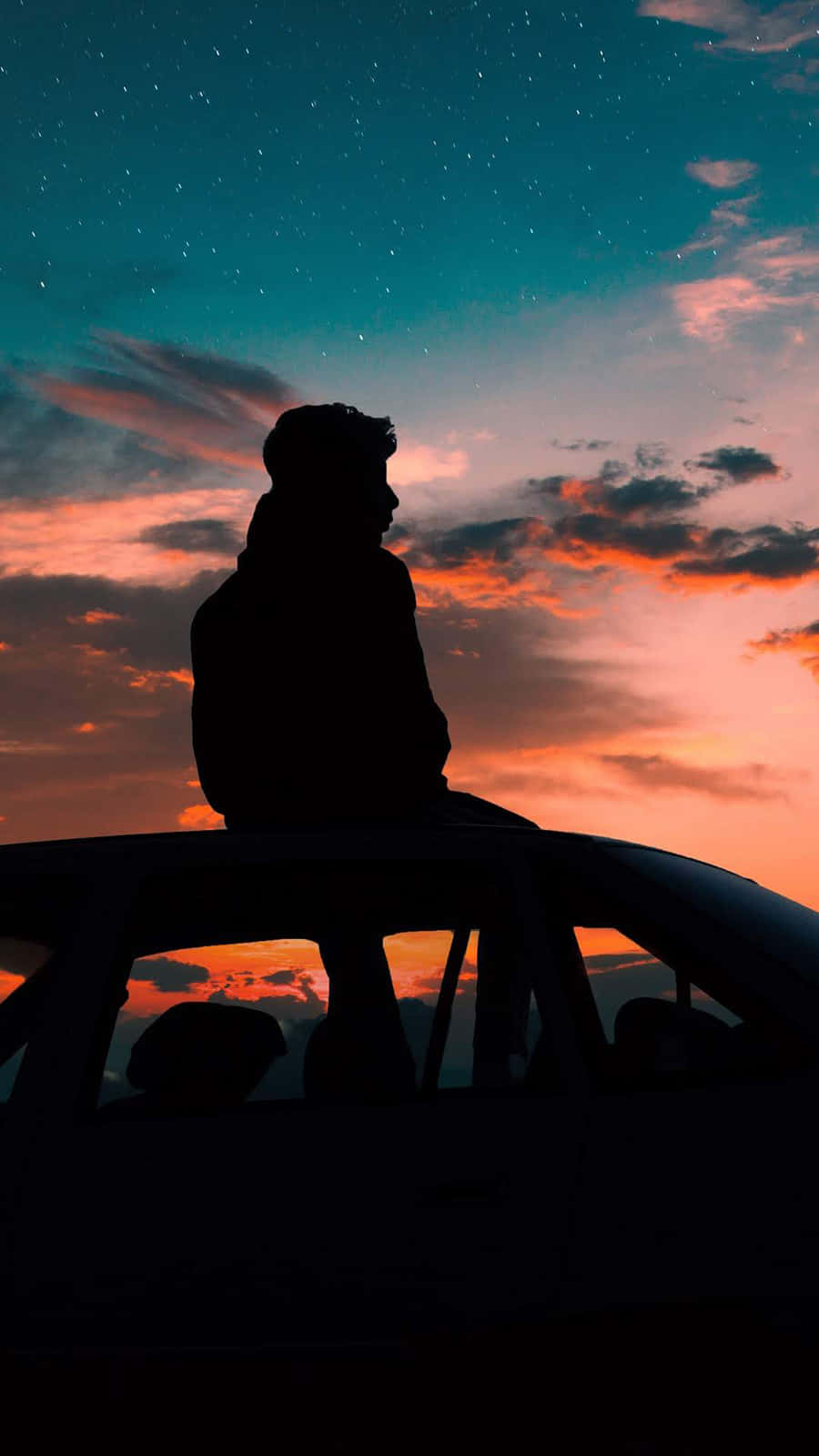 Silhouette 桌布 壁紙 — 一個人以剪影形式坐在車頂上，背景是充滿活力的暮色天空，帶有橙色、粉紅色和藍綠色的星條紋。