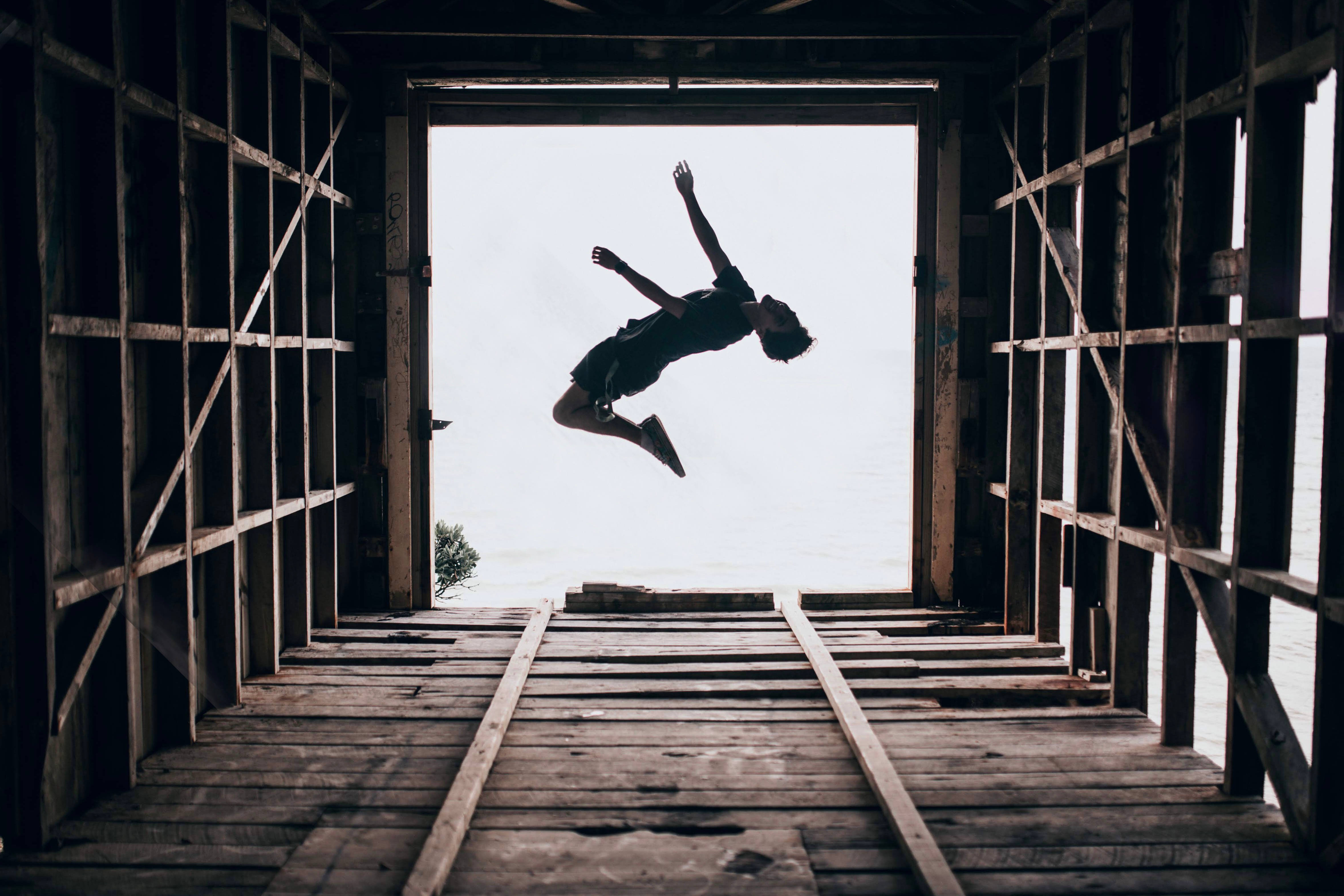 Parkour 桌布 壁紙 — 一個人以剪影形式跳過木結構門口，背後是明亮的天空。