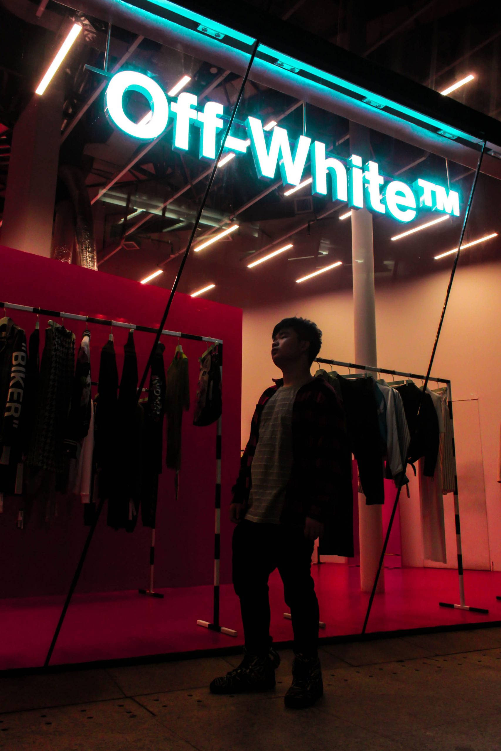 Store 桌布 壁紙 — 一個人以剪影站在發光的 Off-White 商店招牌前，背景是霓虹燈和紅牆。