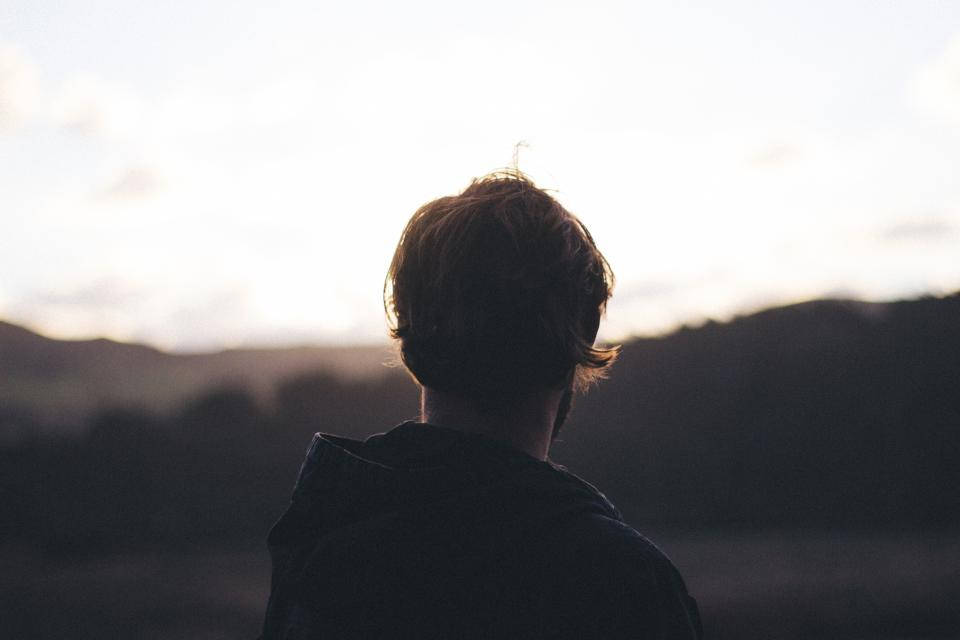 Sad Alone 桌布 壁紙 — 一個人以剪影站立，背景是遠山之上柔和發光的日落。