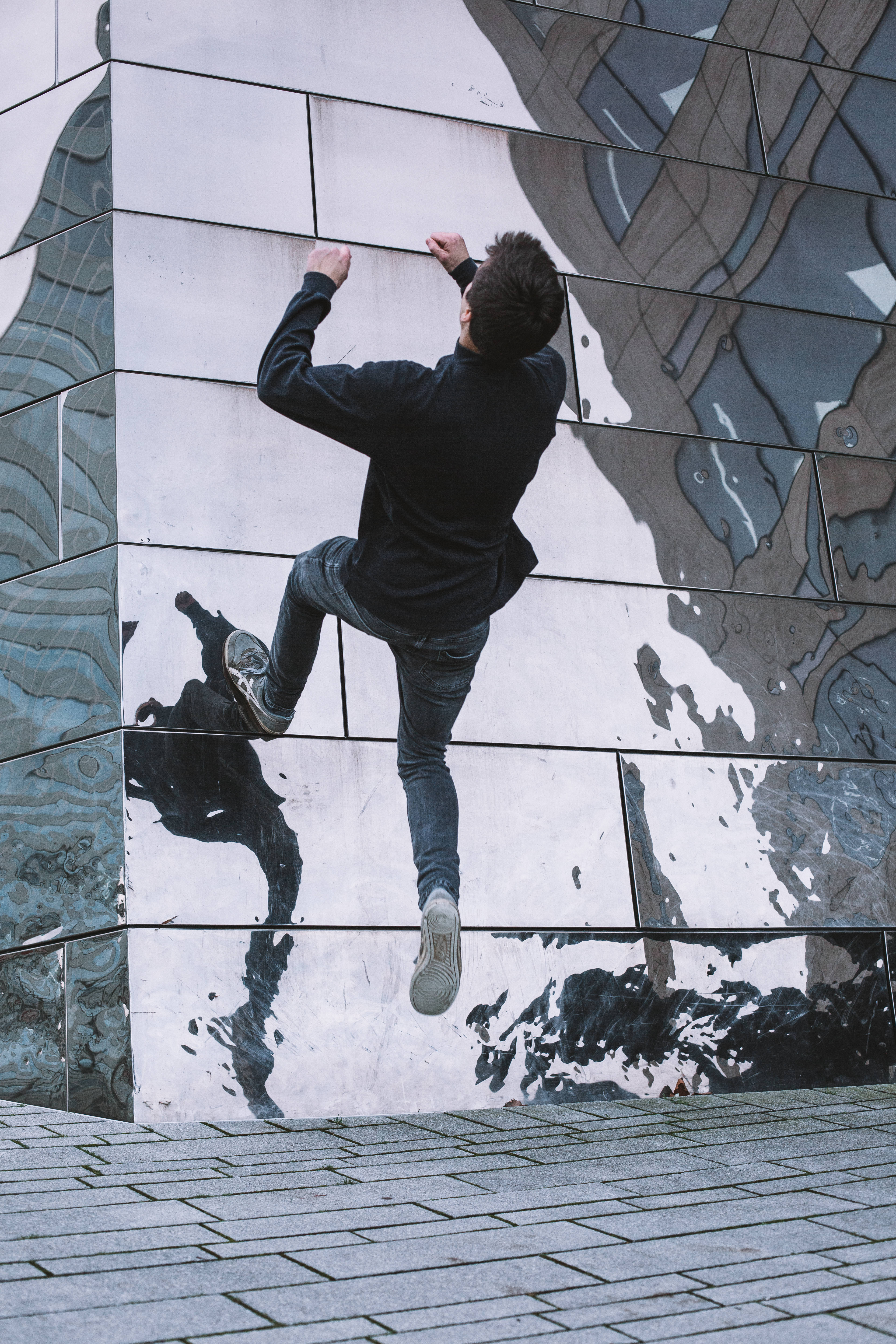 Parkour 桌布 壁紙 — 一個人以動態動作和城市粗獷感攀爬反光瓷磚牆。