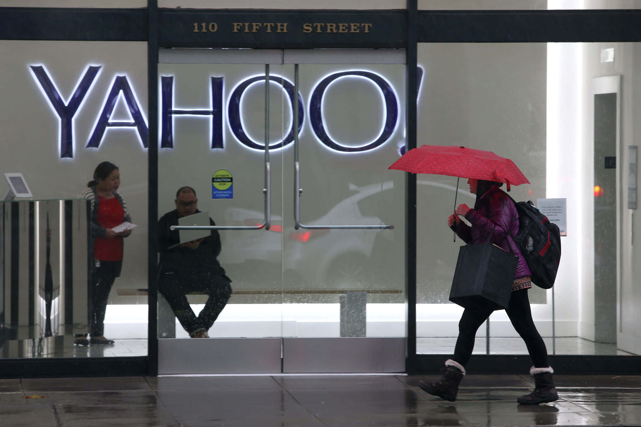 Yahoo 桌布 壁紙 — 一個人在下雨天撐著紅色雨傘走過玻璃幕牆的Yahoo辦公大樓。