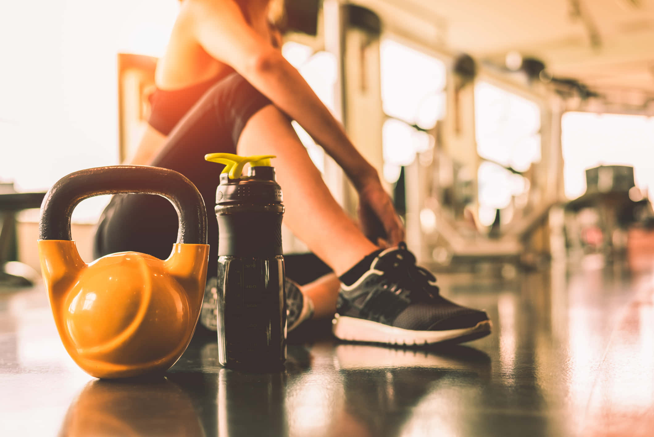 Fitness 桌布 壁紙 — 一個人在健身房地板上休息，旁邊有一個黃色壺鈴和水瓶，陽光透過窗戶照射進來。