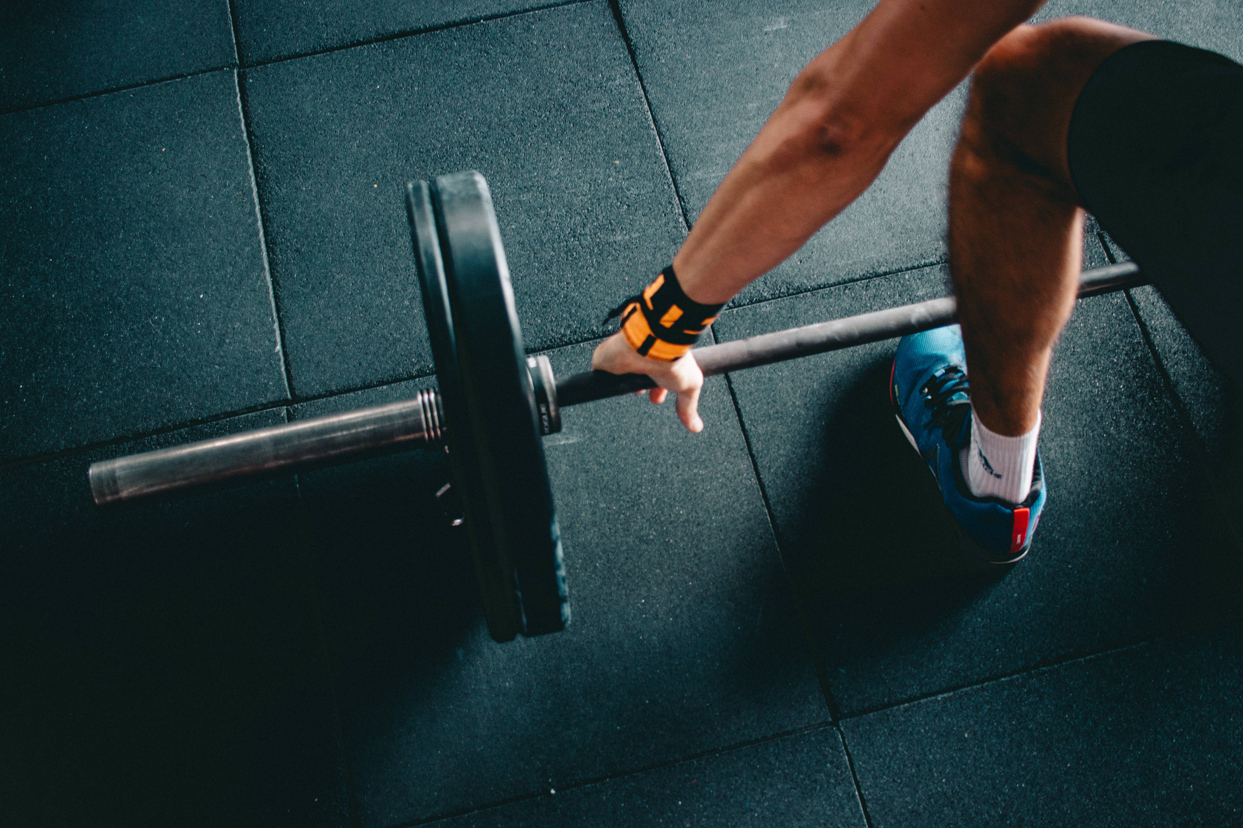 Fitness 桌布 壁紙 — 一個人在健身房準備在深色橡膠地板上舉起帶有槓鈴片的槓鈴。