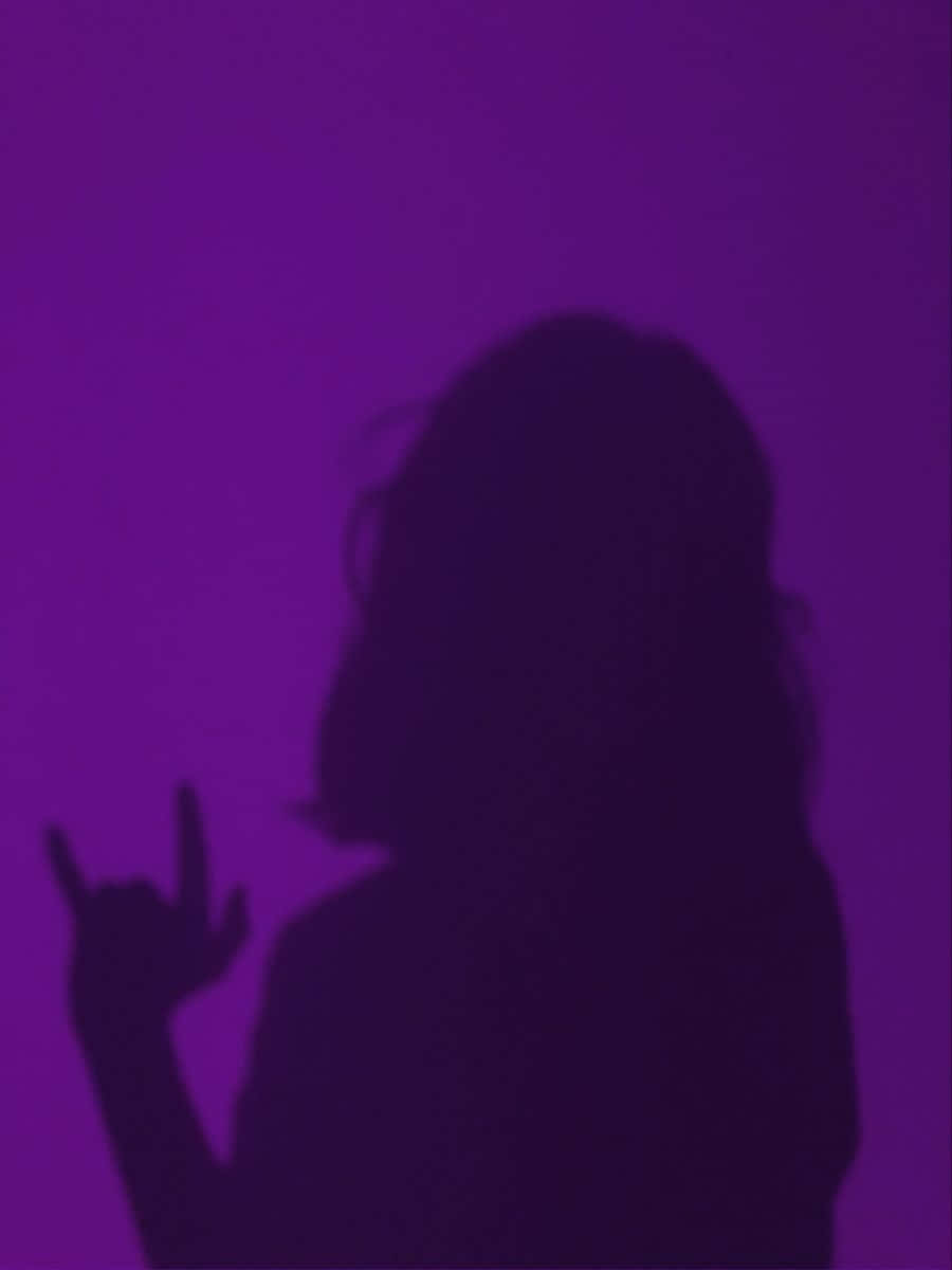 Woman 桌布 壁紙 — 一個人在充滿活力的紫色背景前做出搖滾手勢的剪影。