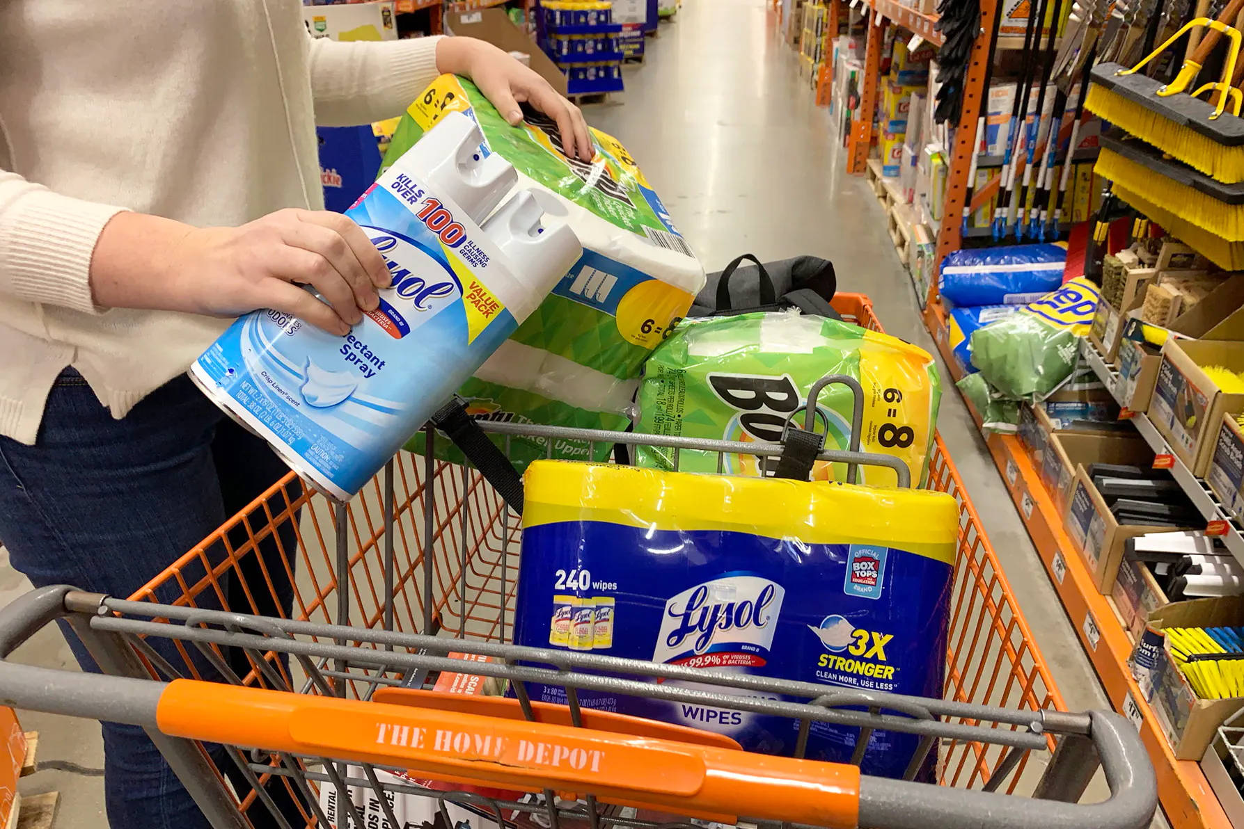 Home Depot 桌布 壁紙 — 一個人在光線充足的通道中，將Lysol濕紙巾和紙巾裝滿Home Depot購物車。