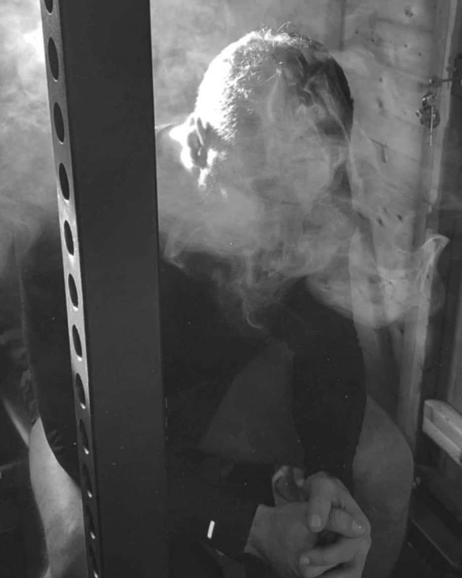 黑白 桌布 壁紙 — 一個人在單色調的昏暗房間裡抽菸，煙霧在他們的臉和手周圍旋轉。