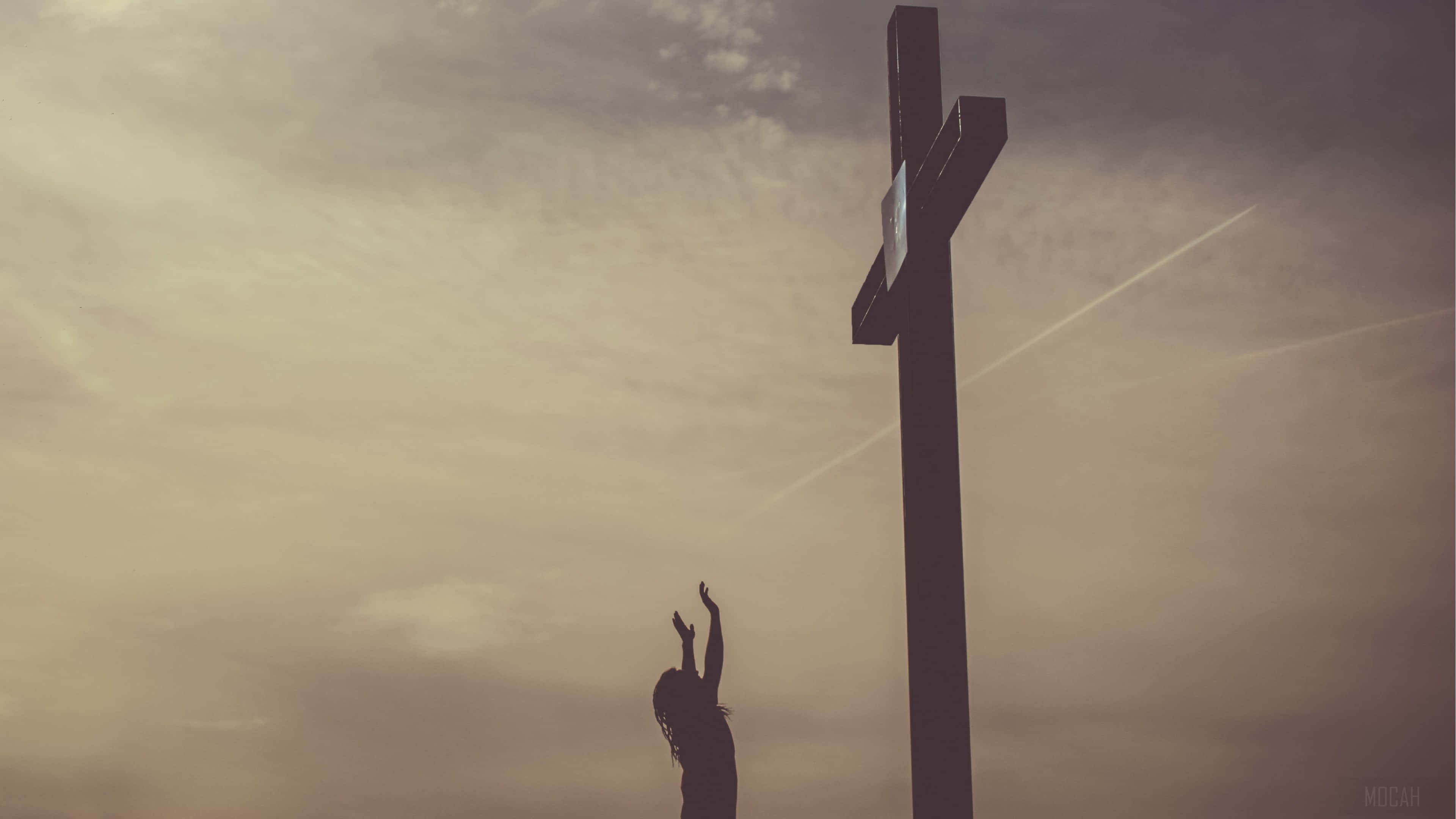 Jesus Saves 桌布 壁紙 — 一個人在多雲的黃昏天空下，在一個大十字架前舉起雙臂祈禱的剪影。
