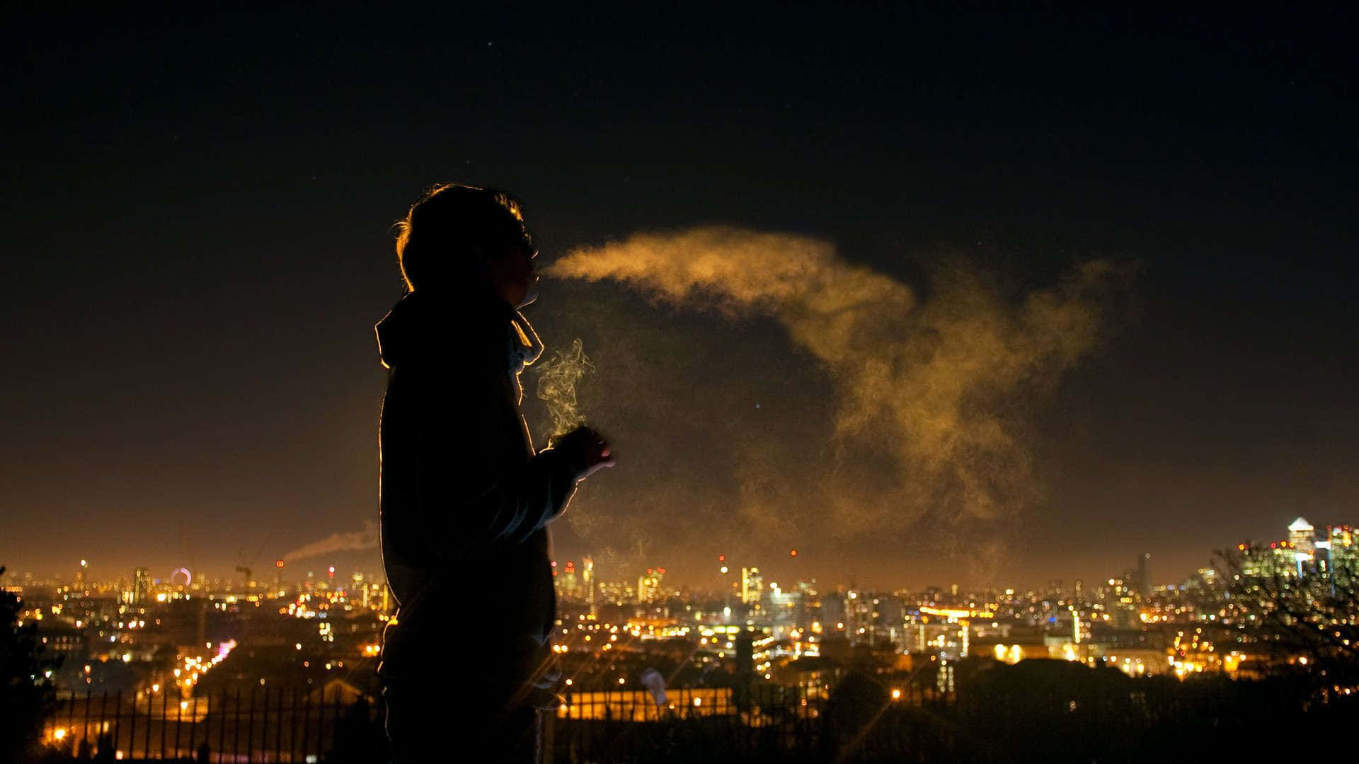 Boy 桌布 壁紙 — 一個人在夜間對著充滿活力的城市天際線呼出溫暖蒸氣的剪影。