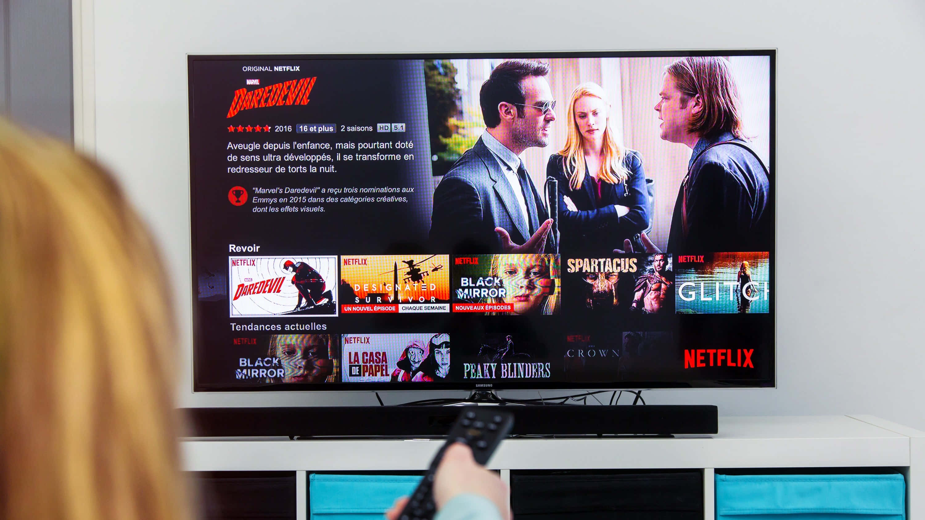 Netflix 桌布 壁紙 — 一個人在大電視上觀看Netflix，顯示著Daredevil的節目頁面和其他系列的縮圖。