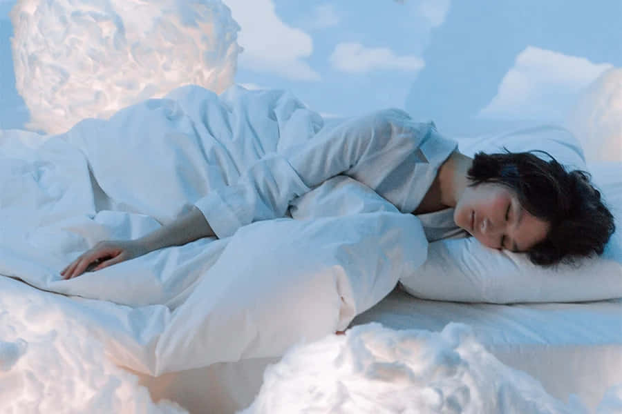 Dreaming 桌布 壁紙 — 一個人在寧靜的藍天下，被柔軟的白雲環繞的床上安詳地睡著。