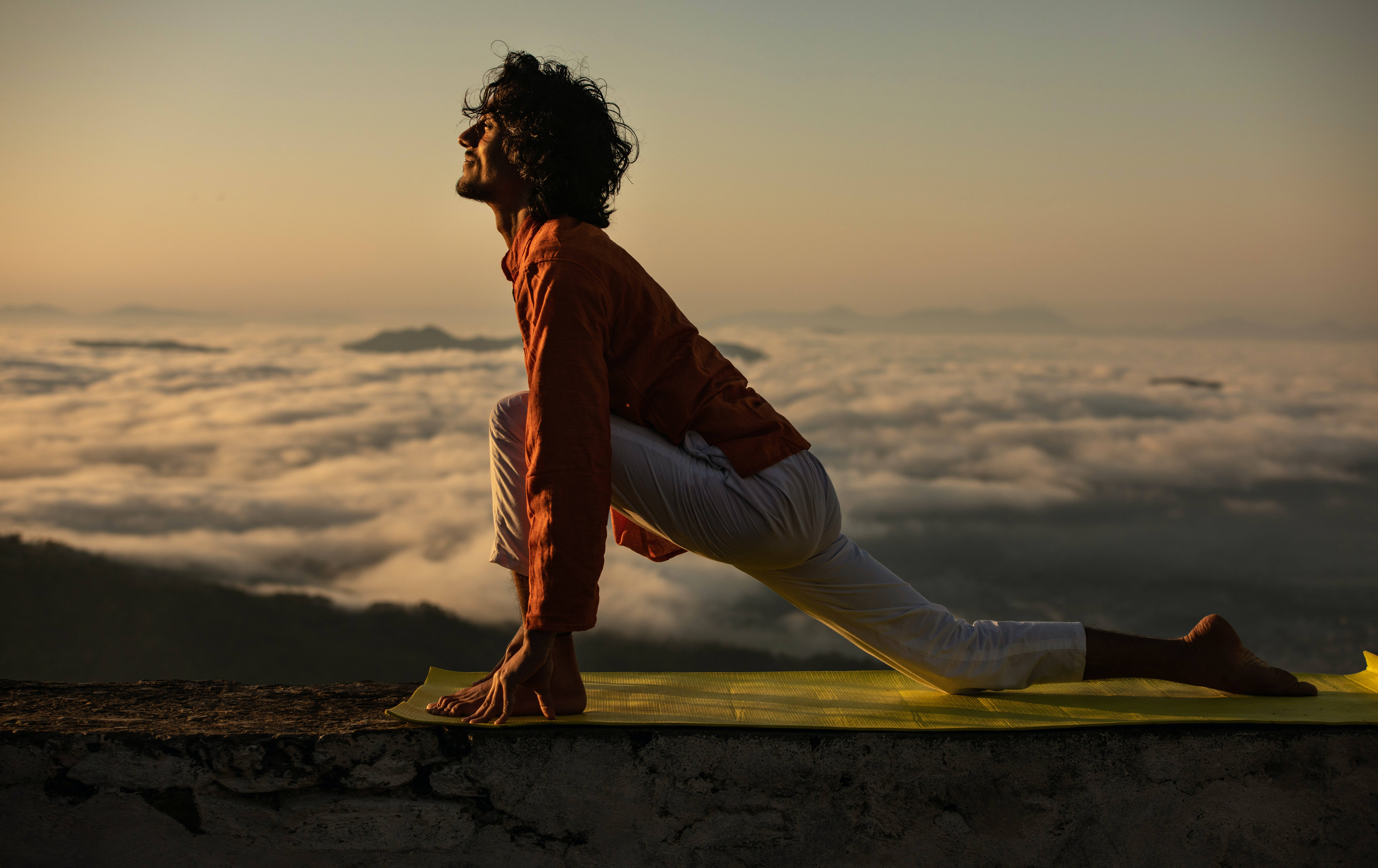 Fitness 桌布 壁紙 — 一個人在日出時分，於雲海之上的山崖邊練習瑜伽，溫暖的金色光芒灑落。