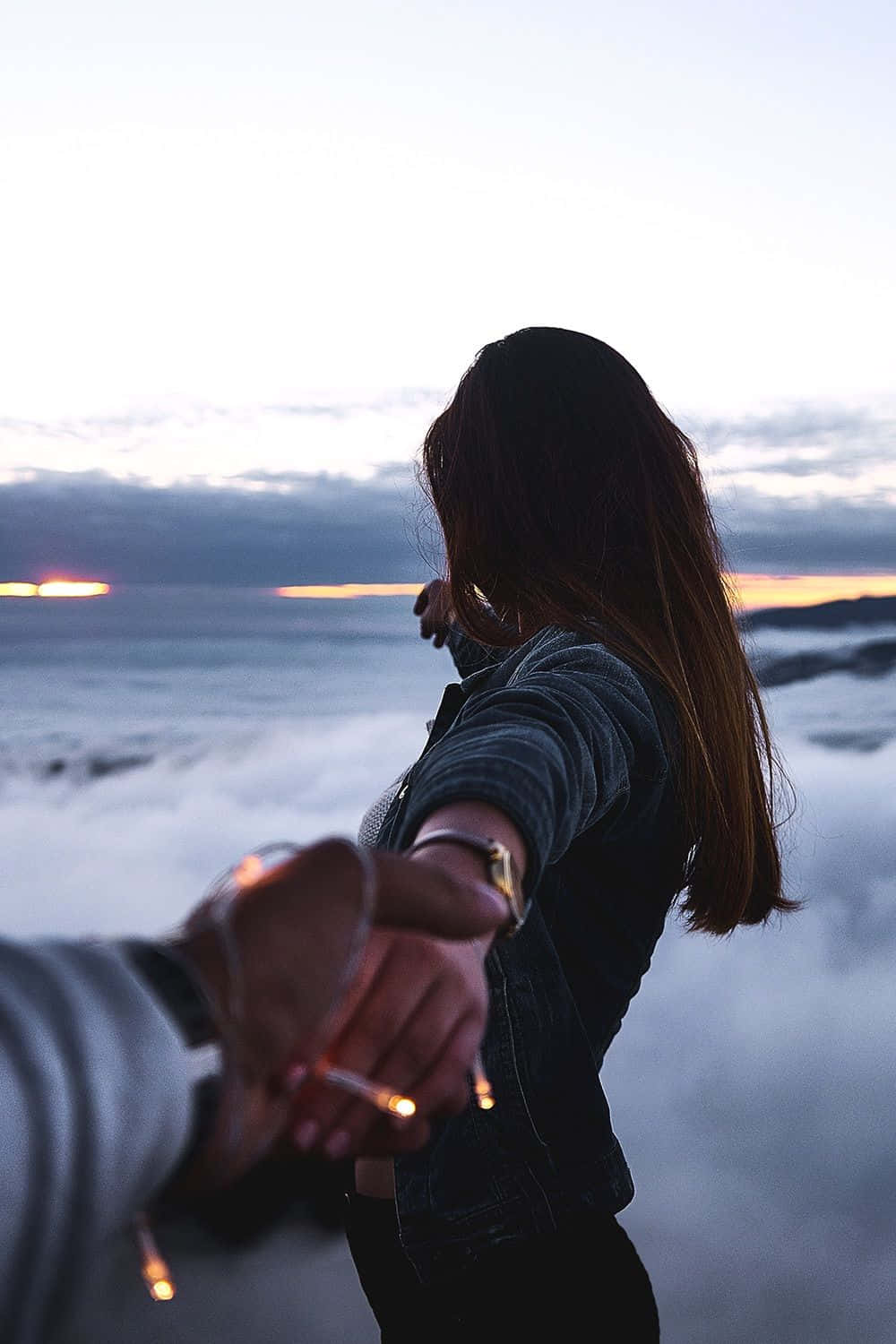 Relationship 桌布 壁紙 — 一個人在日落時分於霧氣瀰漫的海岸懸崖上與另一個人牽手，在發光的地平線襯托下形成剪影。