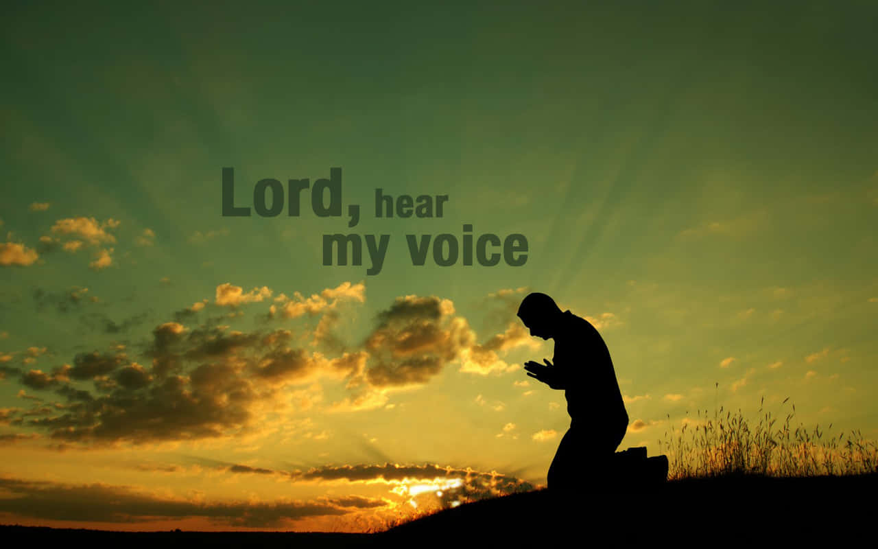 Praying 桌布 壁紙 — 一個人在日落時分跪在草地上祈禱的剪影，伴隨著燦爛的金色雲彩和文字 Lord hear my voice。