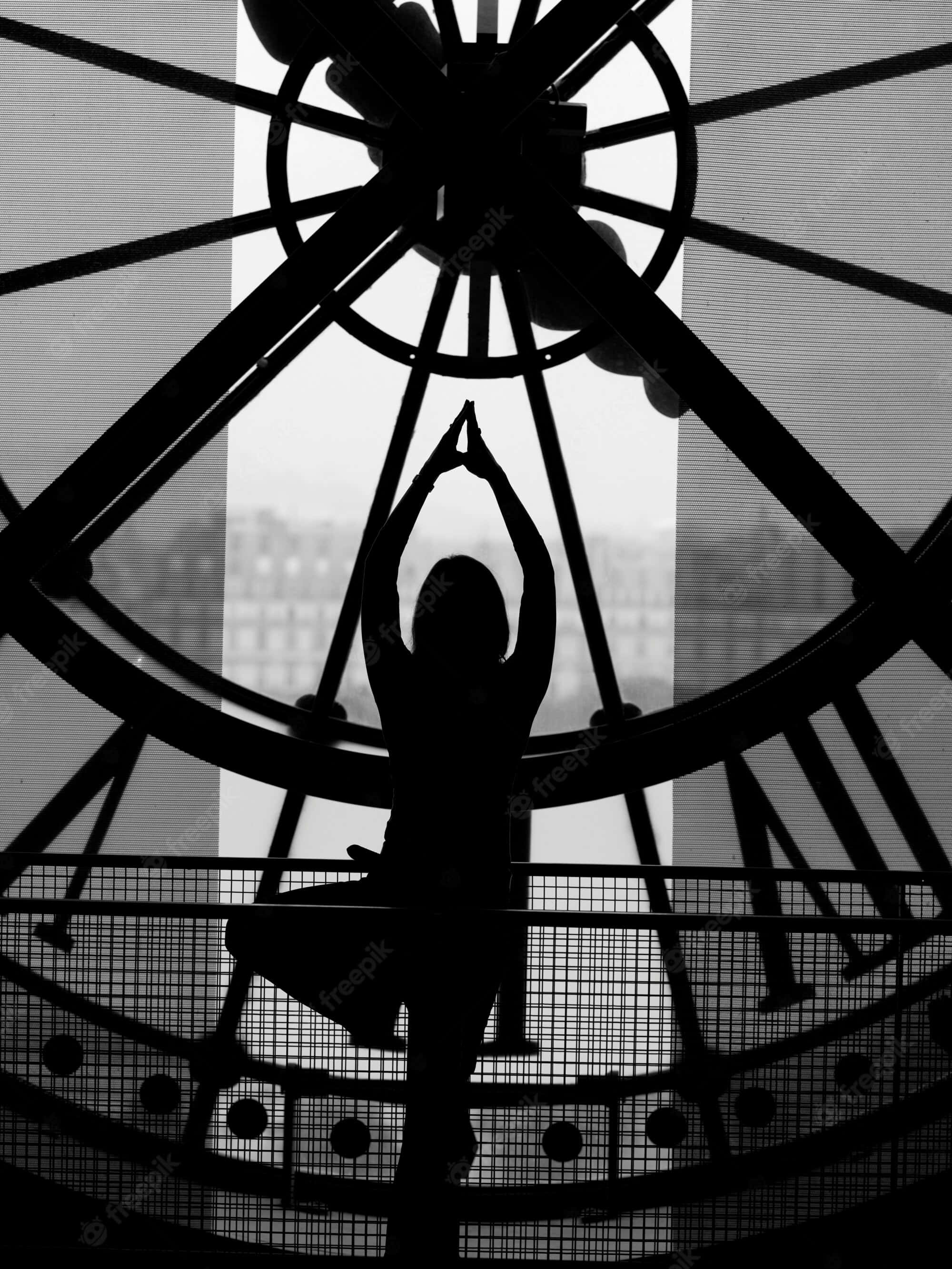 Silhouette 桌布 壁紙 — 一個人在明亮窗戶前，被大型鐘錶結構框住的瑜伽姿勢剪影。