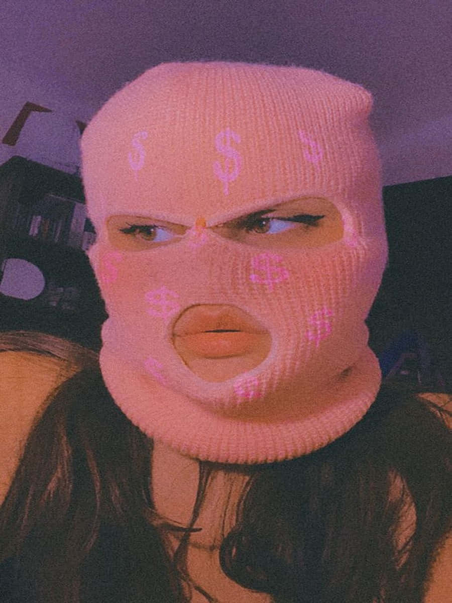 Ski Mask Girl 桌布 壁紙 — 一個人在昏暗的房間裡，在紫色燈光下戴著帶有美元符號的粉紅色針織巴拉克拉法帽。