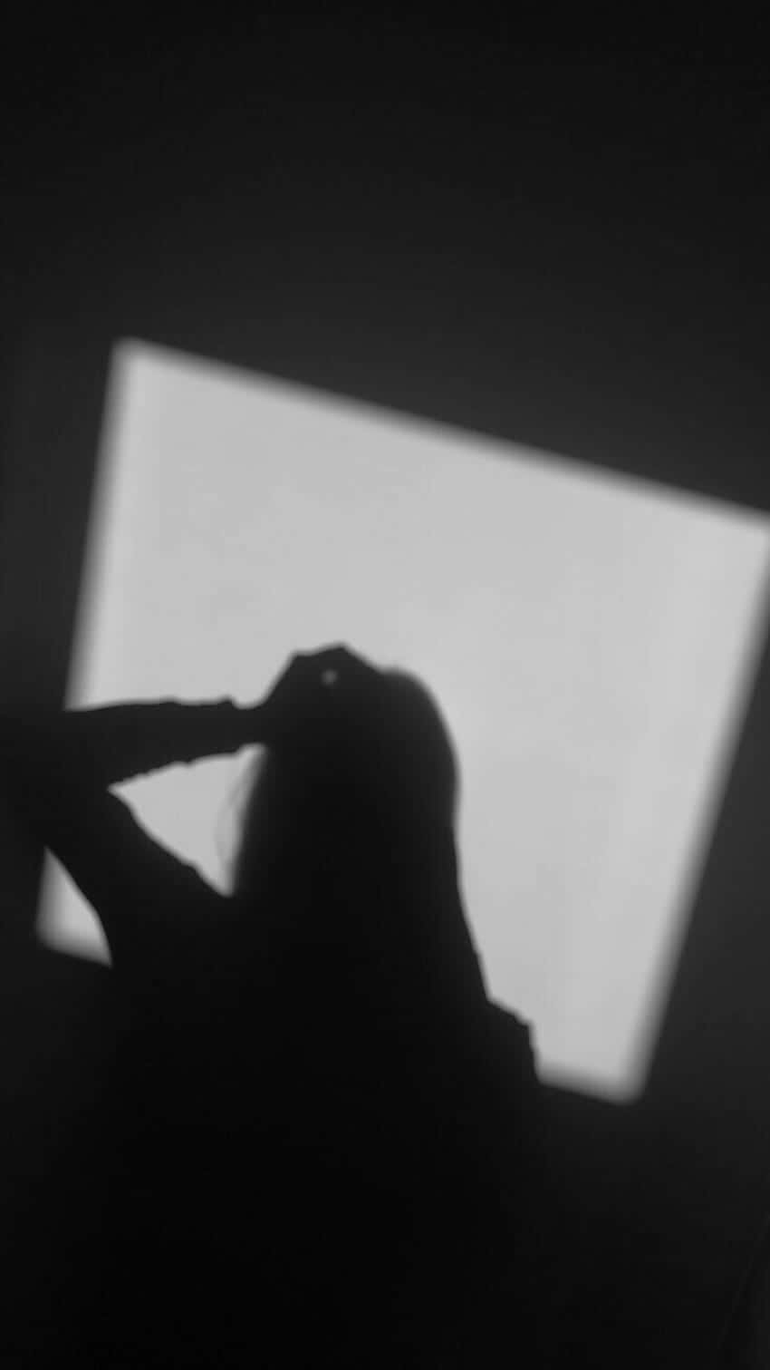 Silhouette 桌布 壁紙 — 一個人在昏暗的房間裡，雙手靠近頭部，在明亮的窗戶上投射出鮮明的黑白剪影。