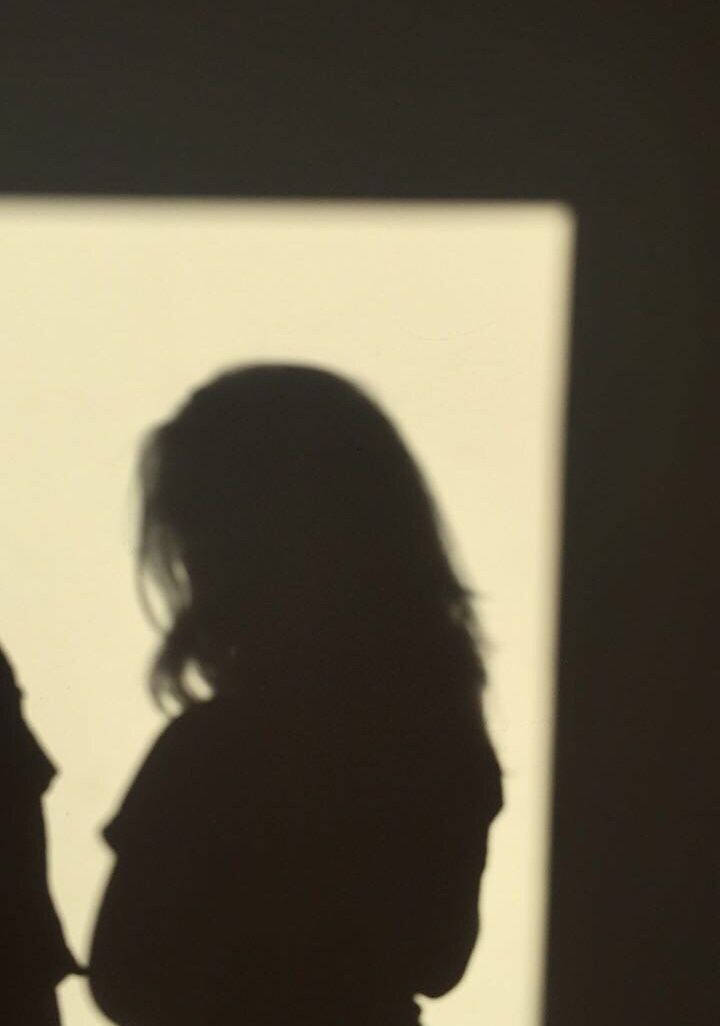 Woman Silhouette 桌布 壁紙 — 一個人在昏暗的房間裡，飄逸的頭髮在明亮的窗戶上投下柔和的剪影。