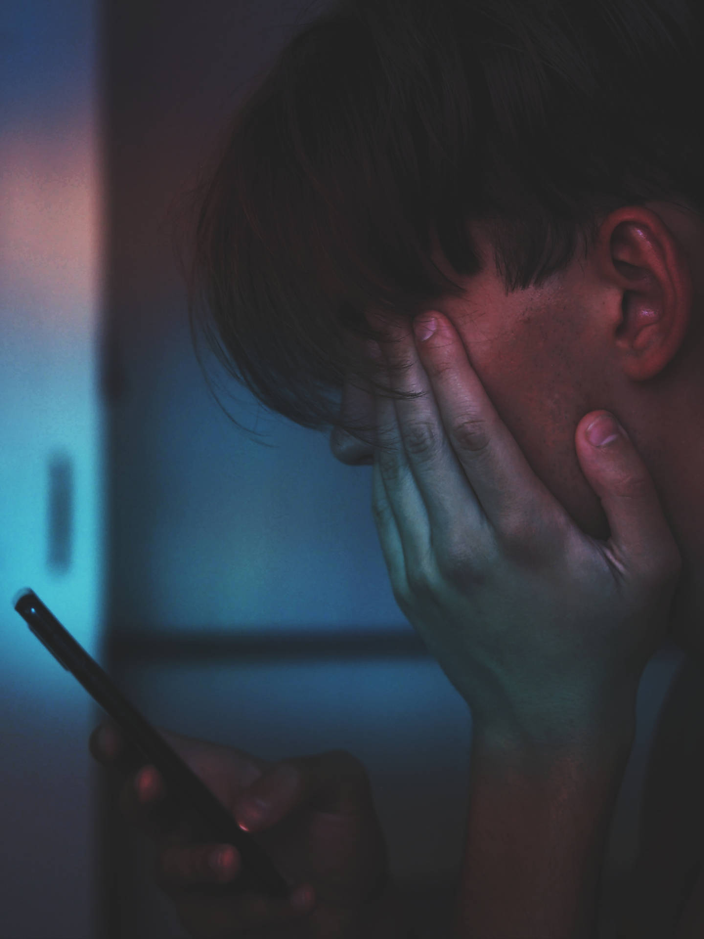 人在昏暗藍光下拿著電話並遮住臉 — 4K 動漫手機壁紙 壁紙