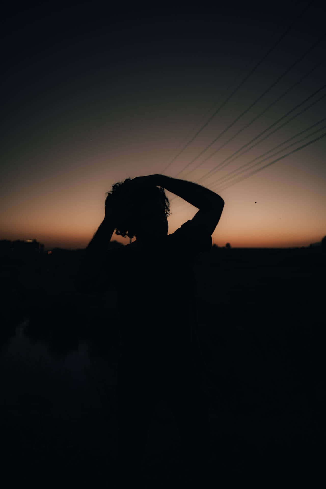 Sunset Aesthetic 桌布 壁紙 — 一個人在暮色天空和電線下的剪影，雙手放在頭髮上。