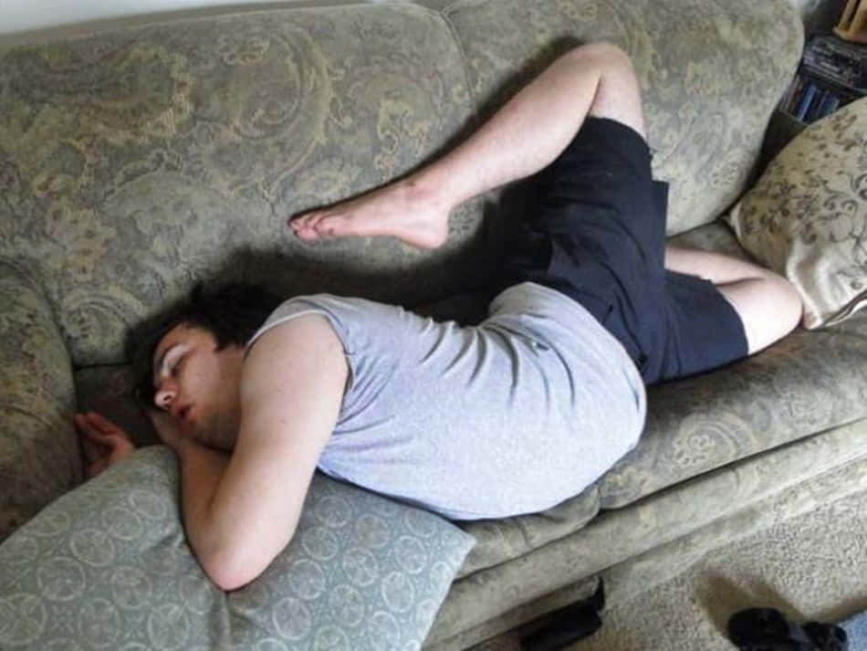 搞笑 桌布 壁紙 — 一個人在有圖案的沙發上熟睡，雙手收在頭下，雙腿彎曲。
