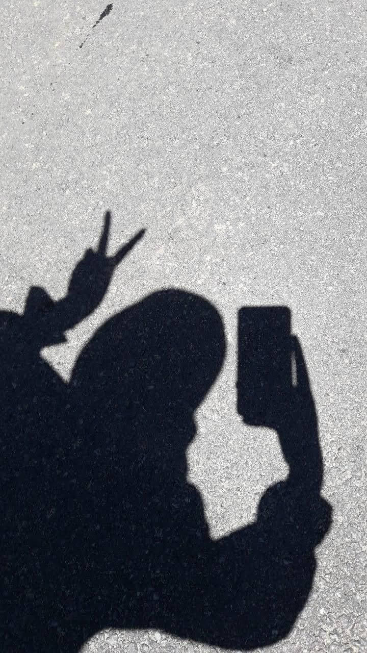 女孩 桌布 壁紙 — 一個人在有紋理的灰色路面上拿著電話做出和平手勢的大膽黑色影子。