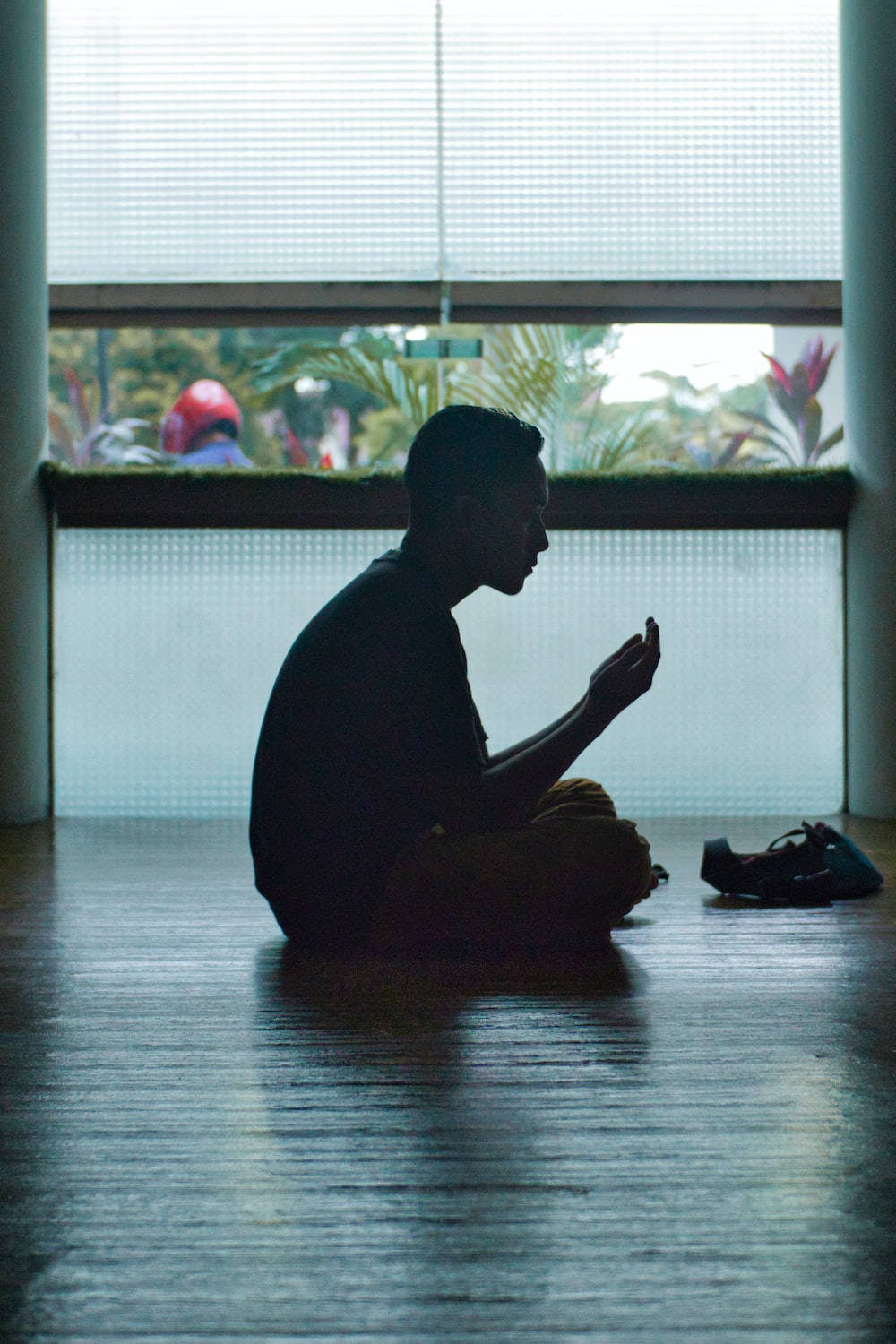 一個人在木地板上祈禱姿勢，靠近窗戶，外面有植物。 — 宗教動圖 壁紙