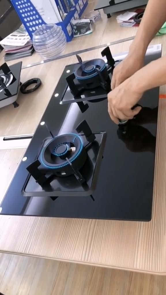 Stove 桌布 壁紙 — 一個人在木質檯面上安裝一個帶有藍色火焰燃燒器的黑色玻璃瓦斯爐。