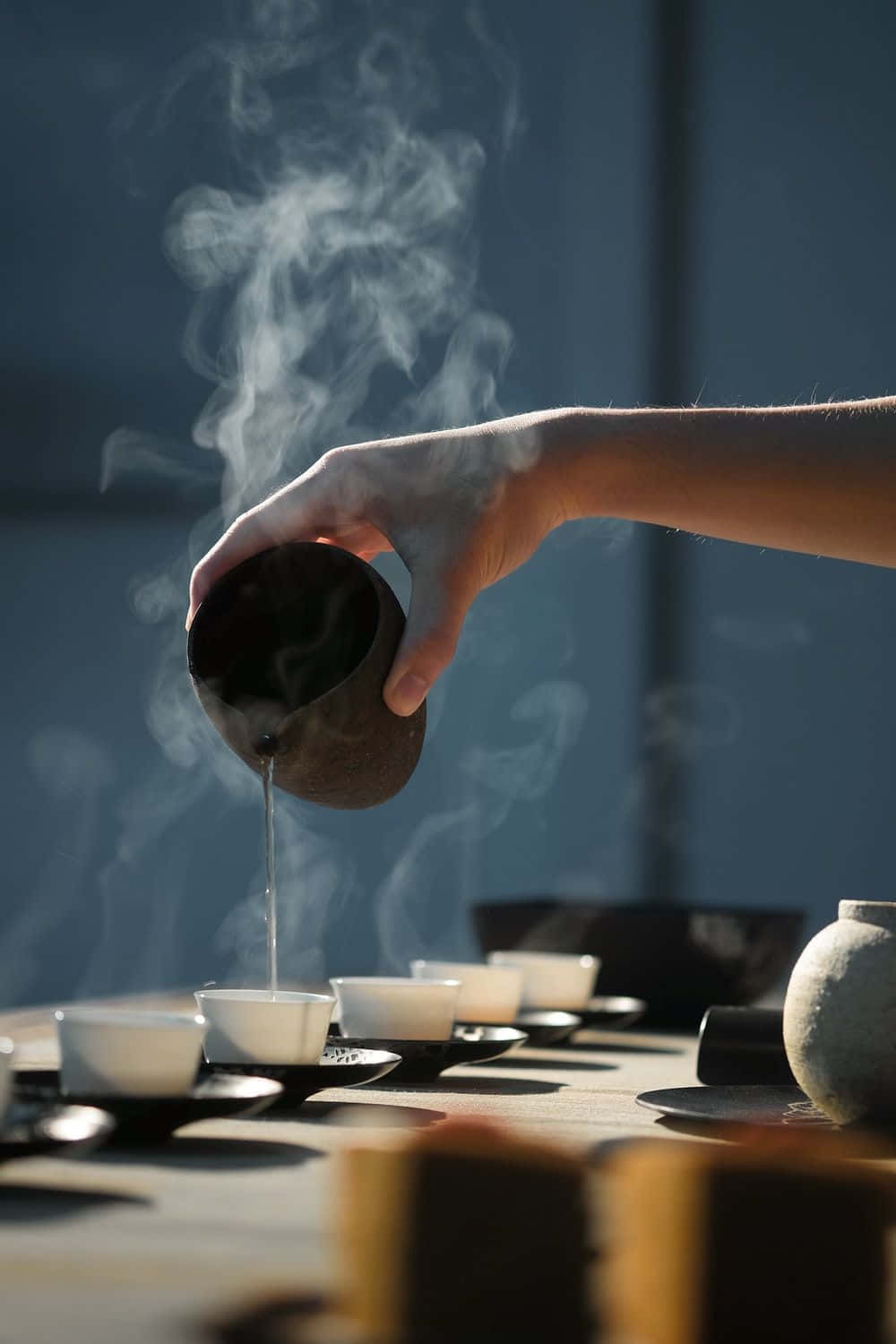 一個人在桌上將茶倒入杯中 壁紙