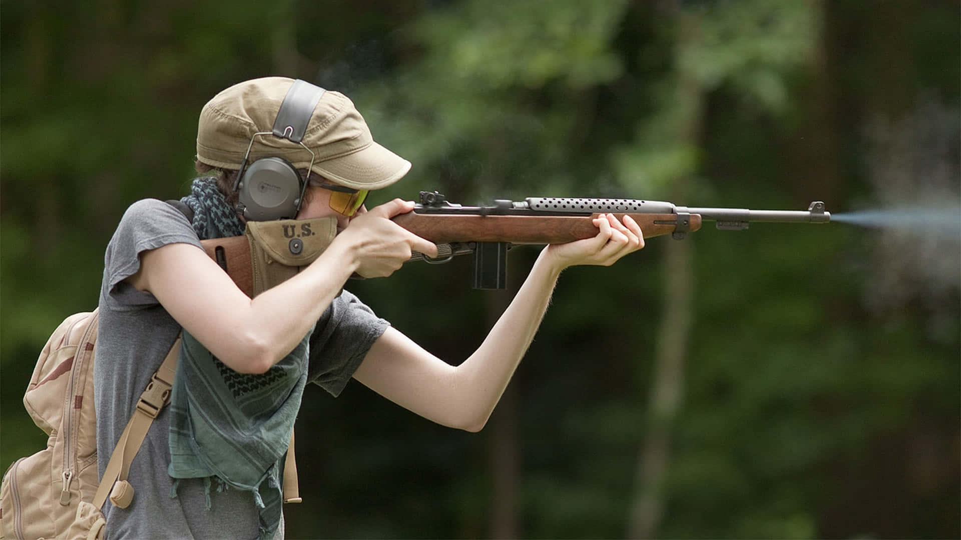 Rifle 桌布 壁紙 — 一個人在森林中開步槍，槍管冒煙，戴著耳罩和帽子。
