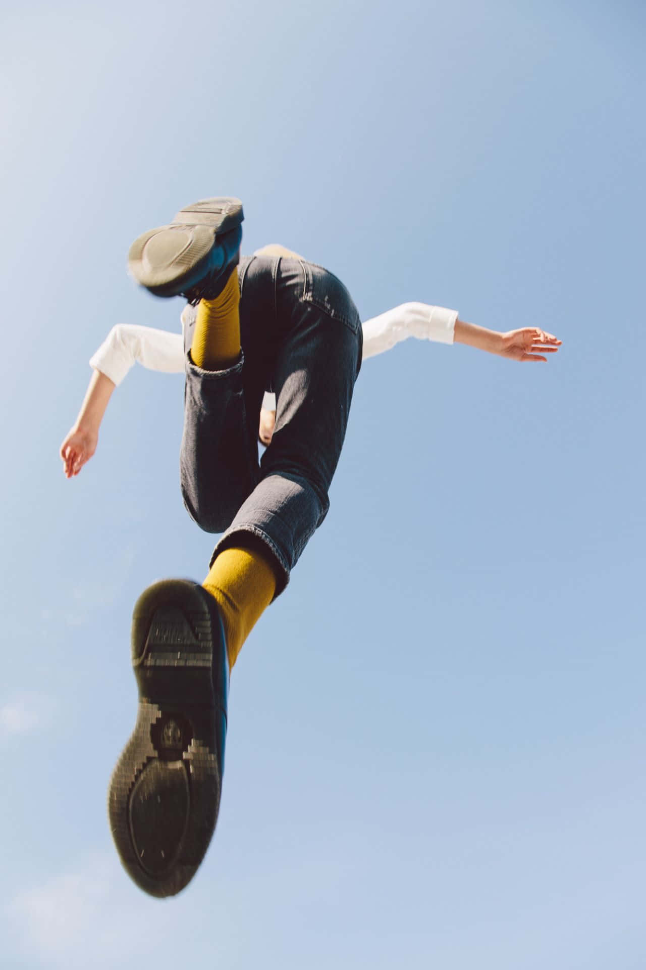 jump 桌布 壁紙 — 一個人在清澈的藍天中，穿著黃色襪子和深色牛仔褲，雙臂伸展。