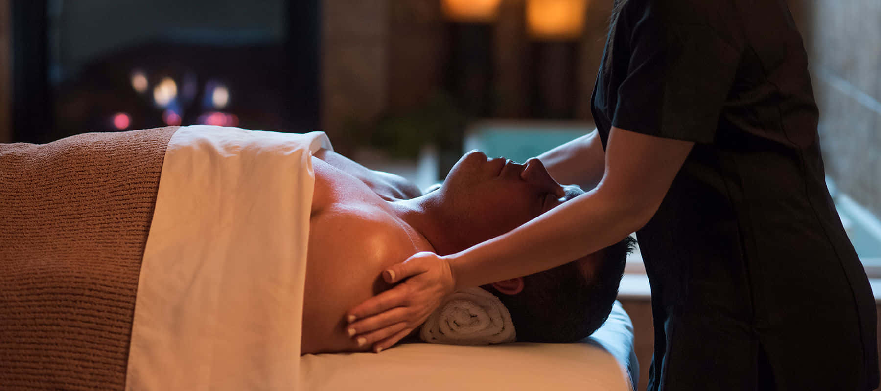 Massage 桌布 壁紙 — 一個人在溫暖燈光的舒適水療中心享受放鬆按摩。