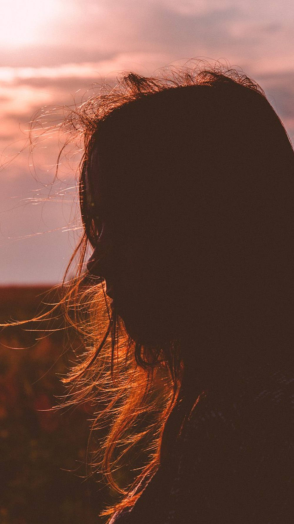 Woman 桌布 壁紙 — 一個人在溫暖的日落天空下，頭髮被風吹動的剪影，天空中有柔和的雲朵。